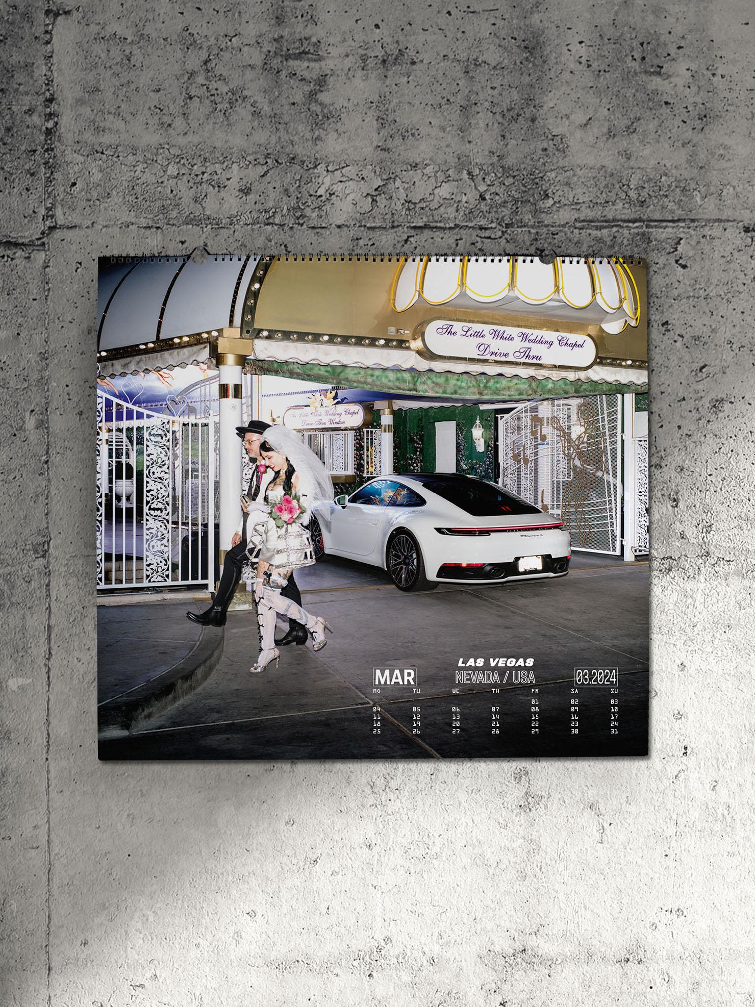 Pictured is a Porsche wall calendar on a gray concrete wall. The calendar shows a white Porsche 911 and a wedding couple.