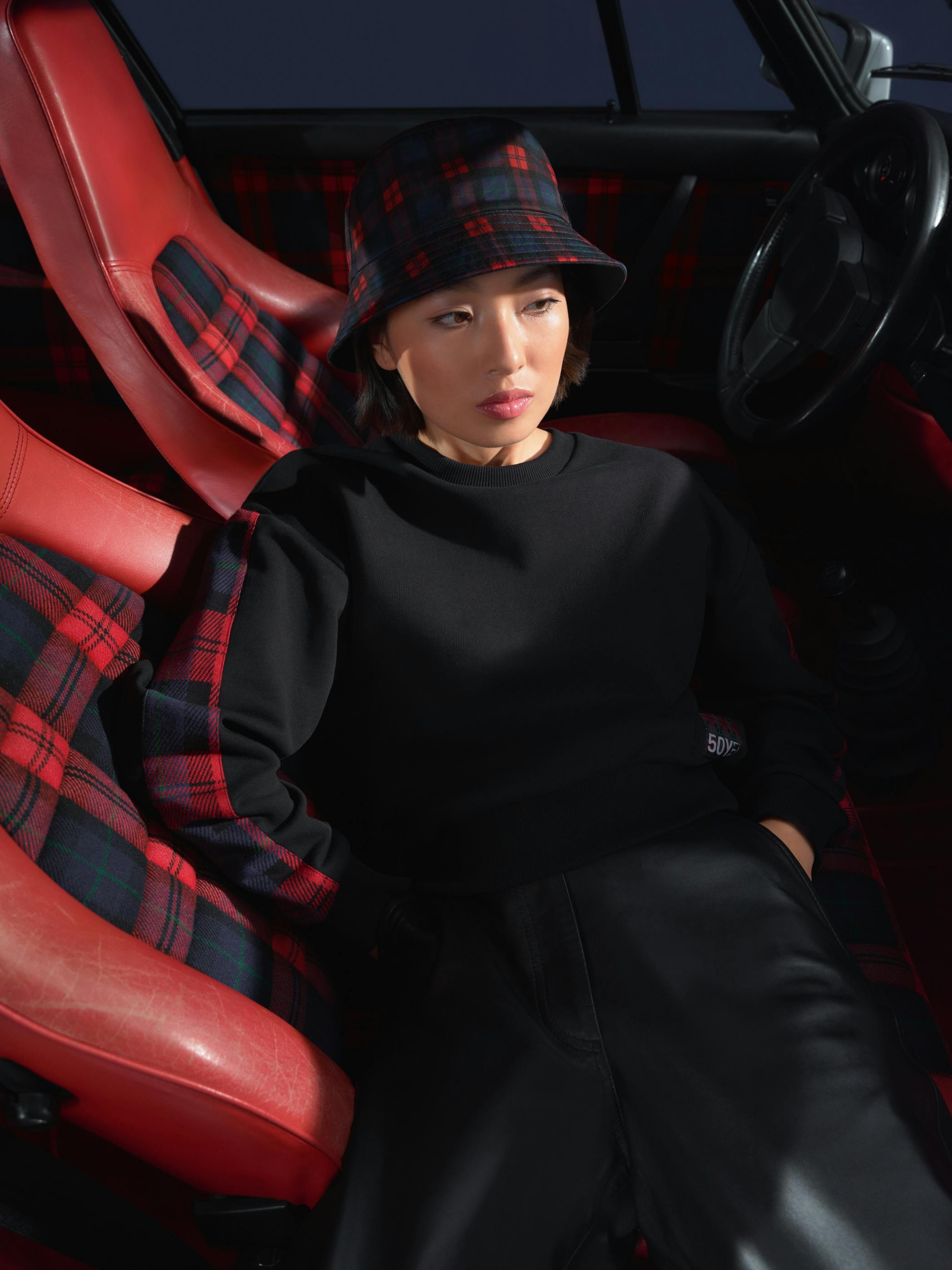 Woman sitting in a historic 911 and wearing clothing from Turbo No. 1 collection
