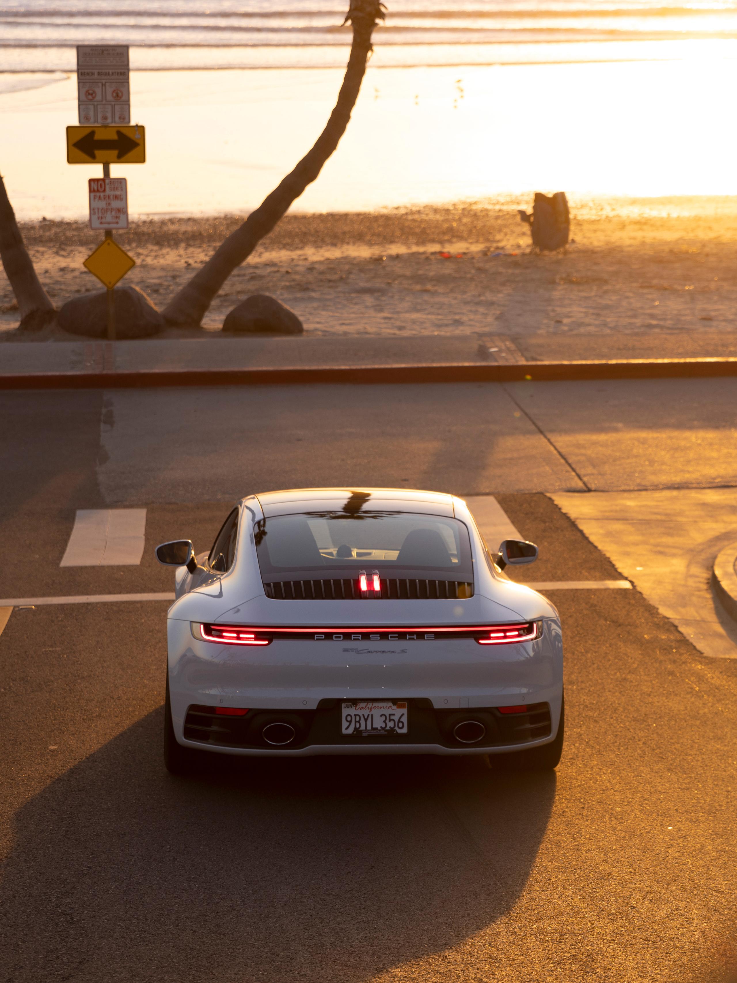 Pictured is a silver Porsche 911 standing in front of a zebra penalty with a sunset