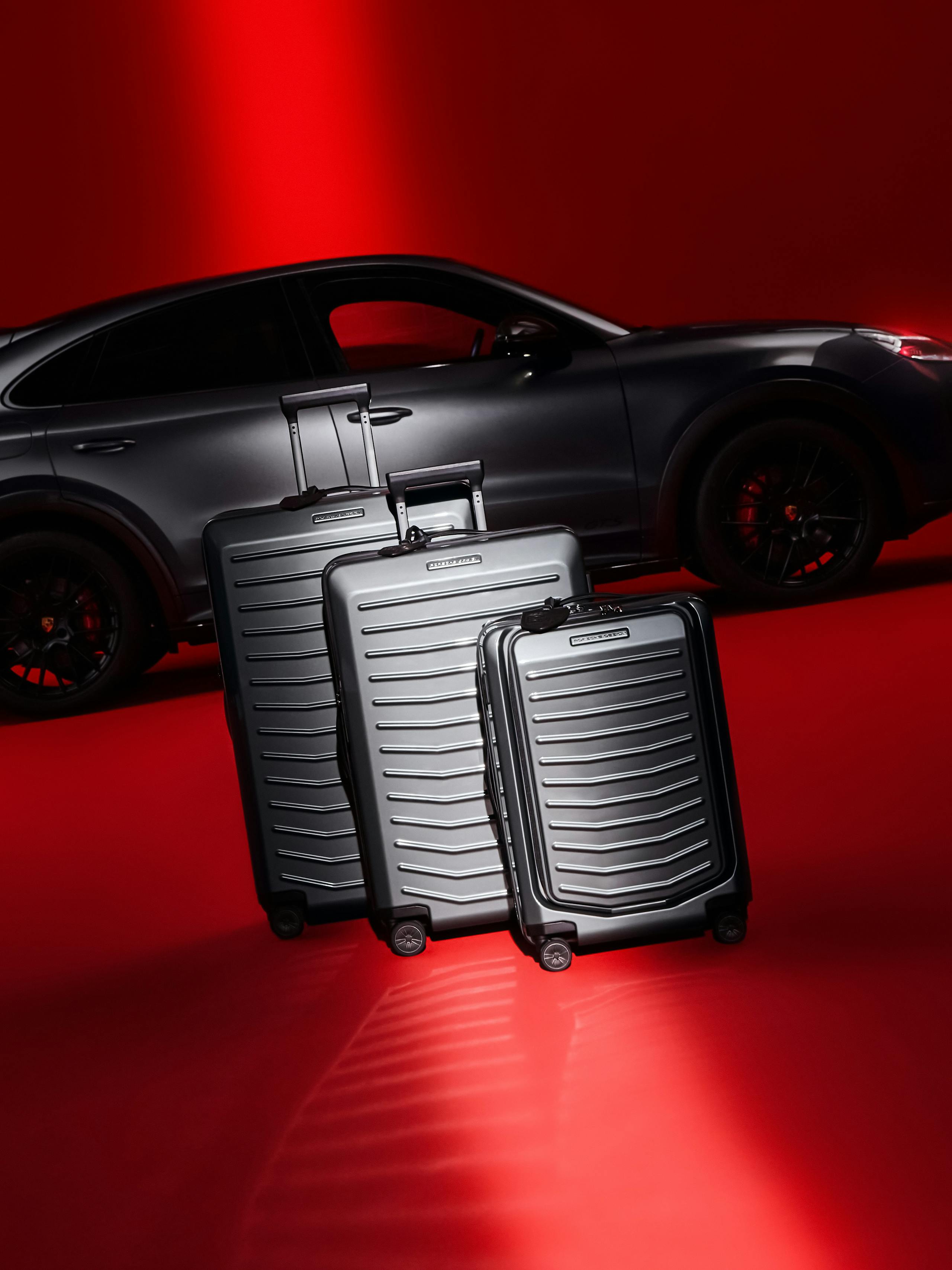 In the picture you can see three suitcases from Porsche Design in three different sizes with a black Porsche Cayenne in the