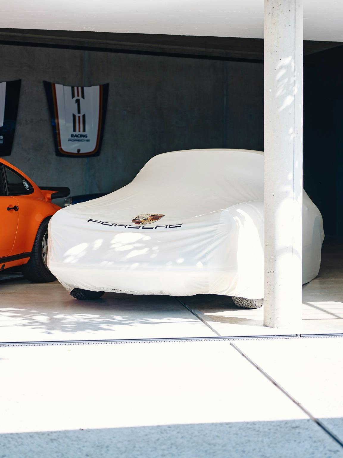 One 911 with a Car cover and one Panamera without Car Cover in a big garage