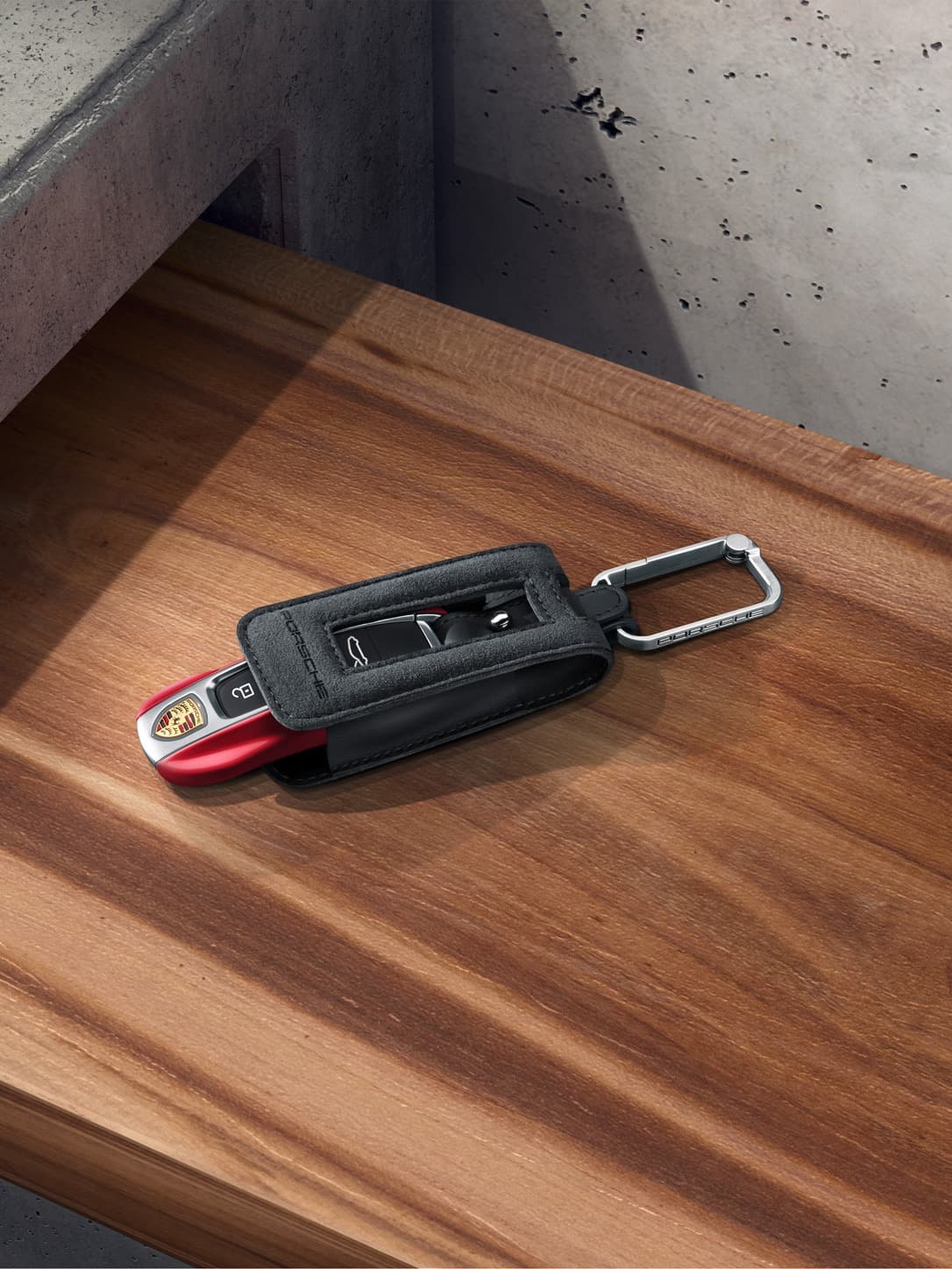 Porsche Tequipment keyring in black with a key in red on a table.