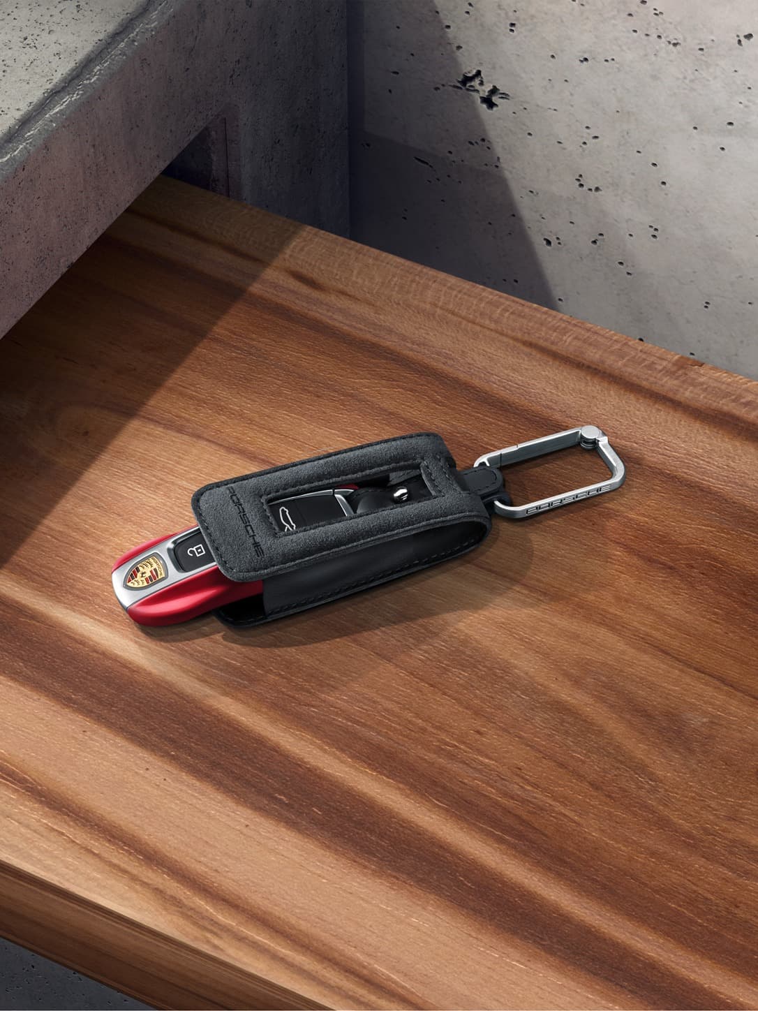 Porsche Tequipment keyring in black with a key in red on a table.
