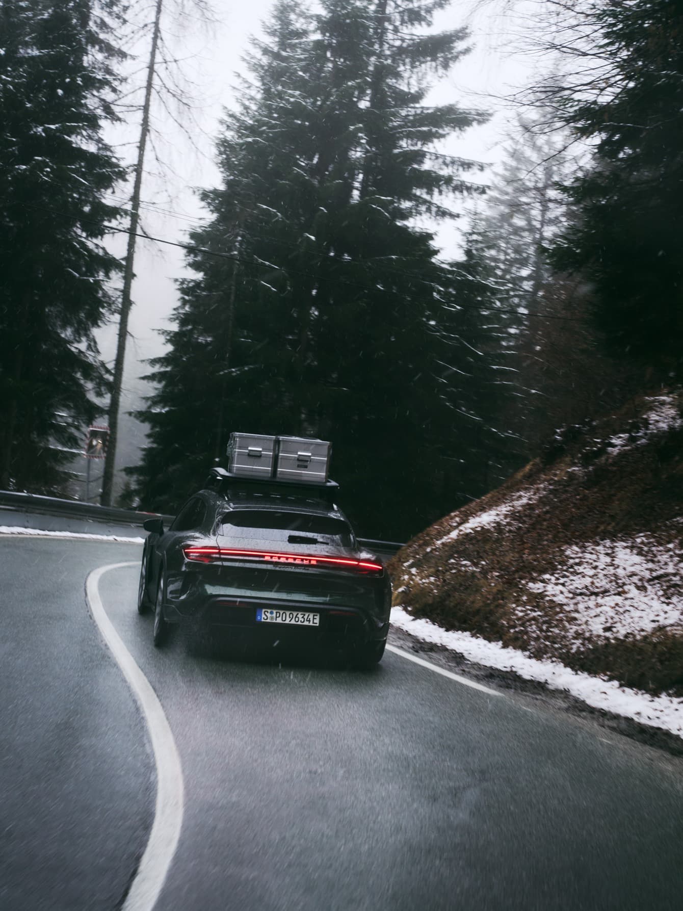 A Porsche car is driving on a road through the forest