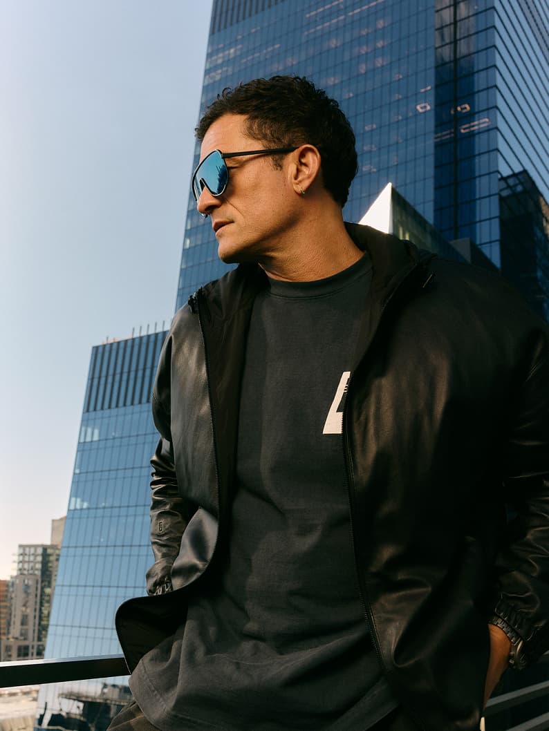 Mann mit Sonnenbrille und dunkler Kleidung vor einer Skyline