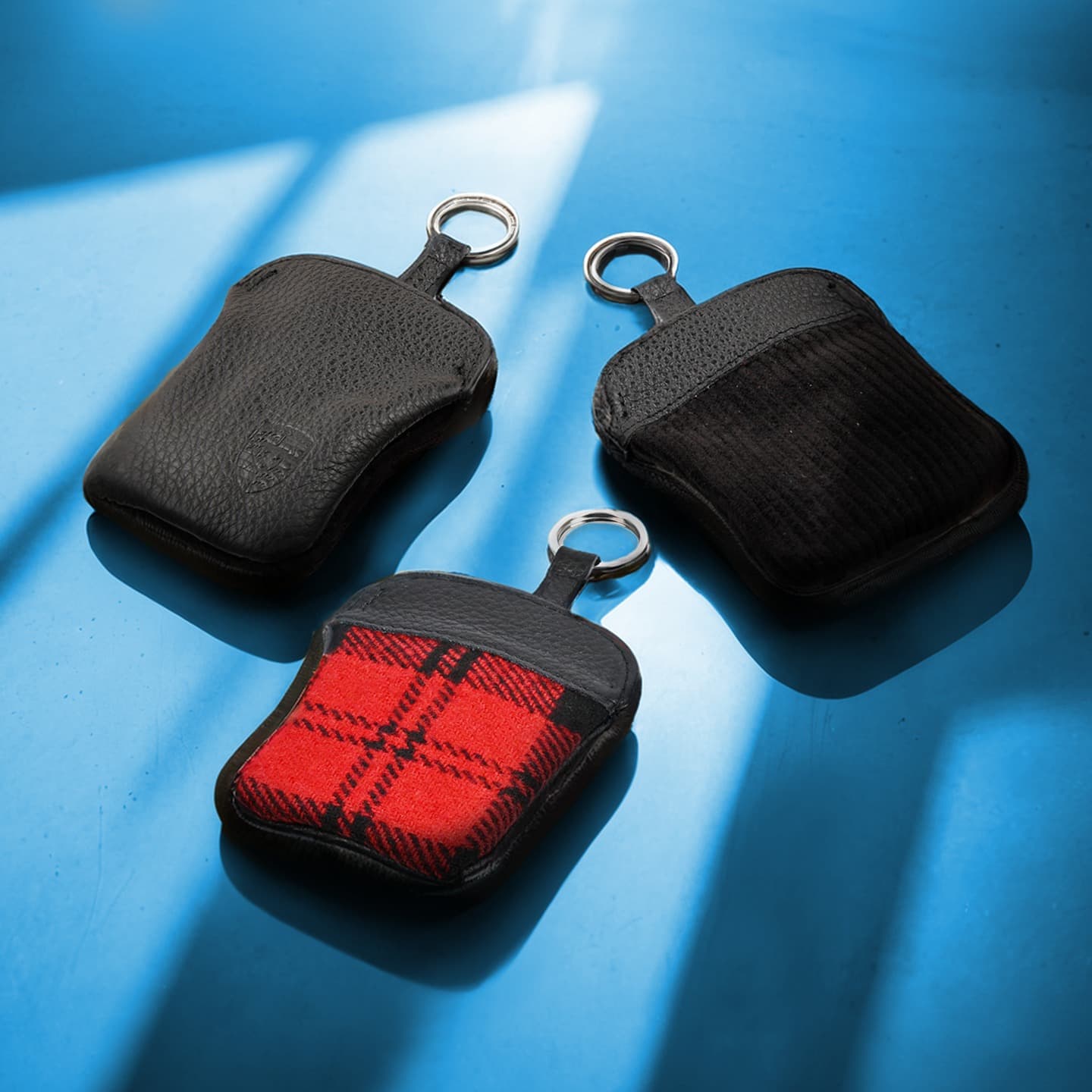 Three Porsche key pouches in the focus on a blue background