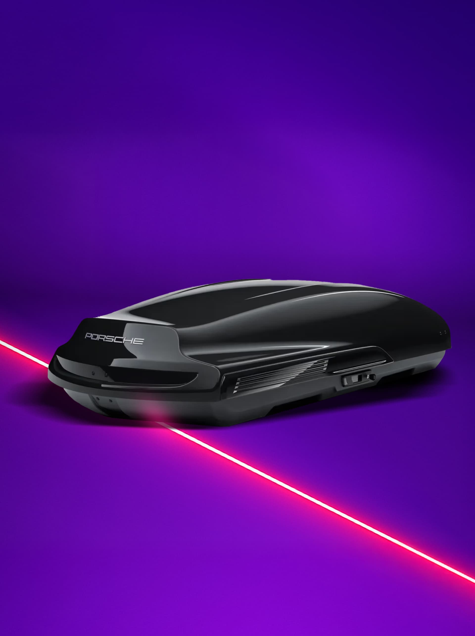 You can see a sleek black Porsche roof box on a vibrant purple background with a red laser line