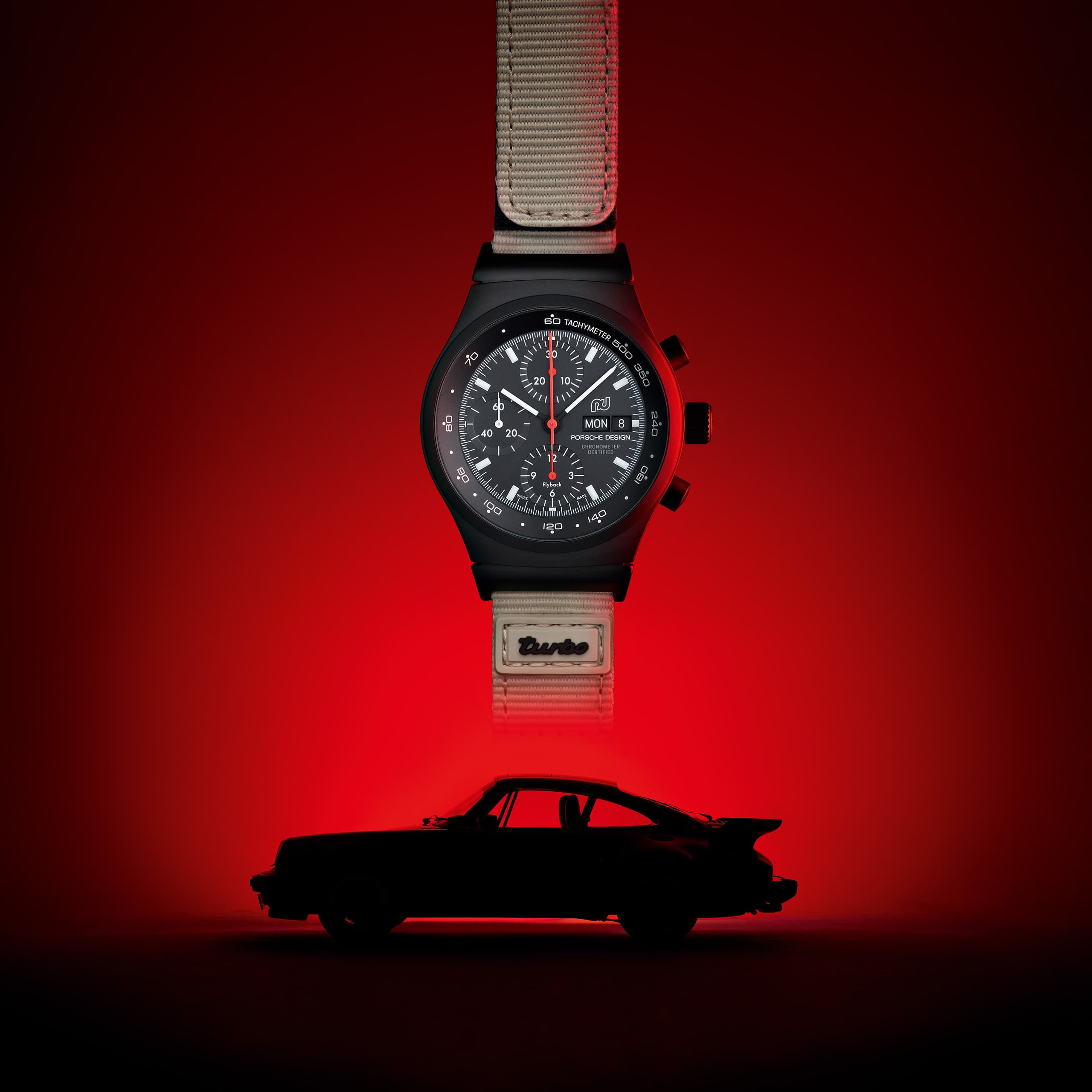 Chronograph 1 - 50 Years 911 Turbo Edition is in front of a silhouette of a Porsche 911 Turbo in black, red background