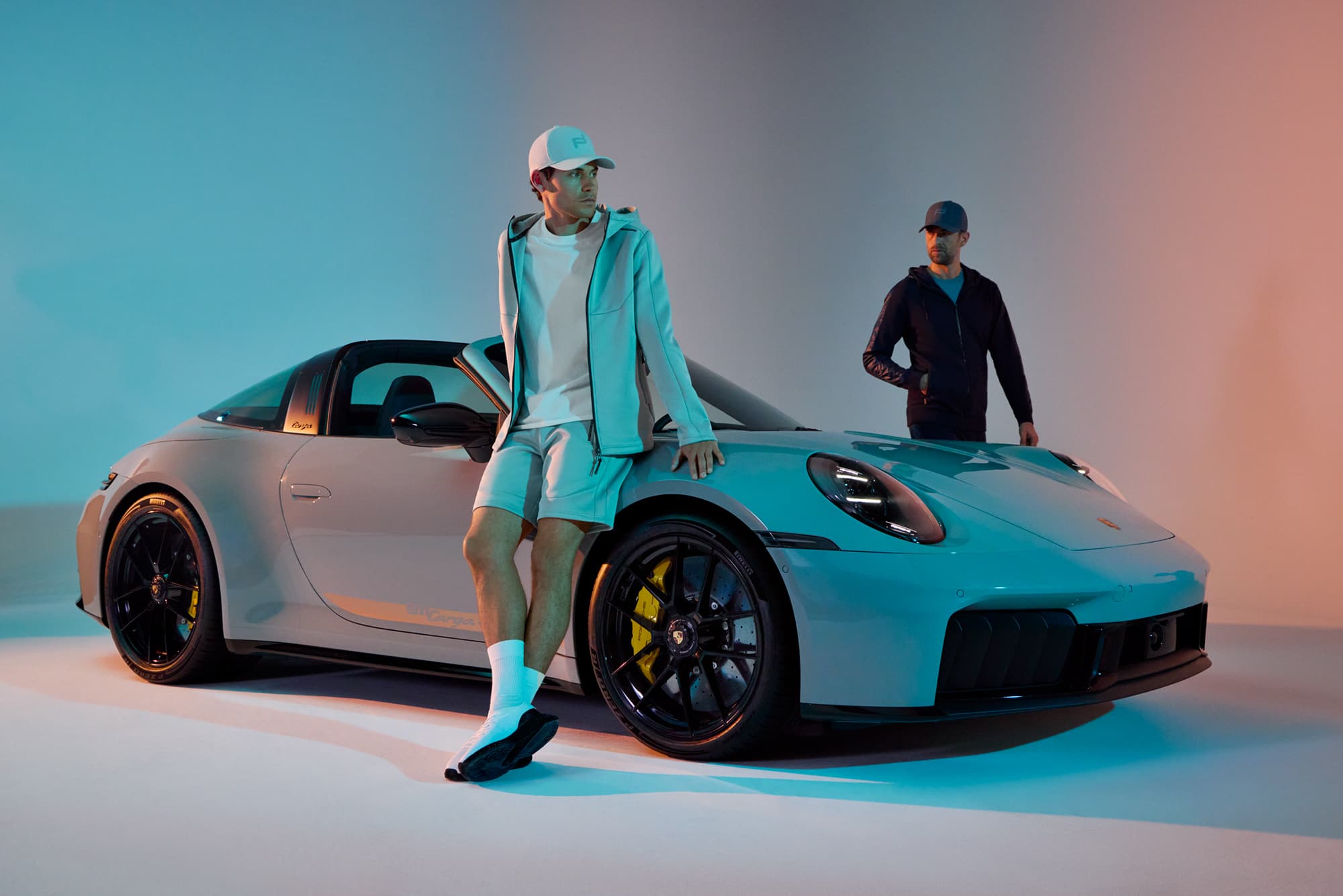 Two men standing netxt to a Porsche car