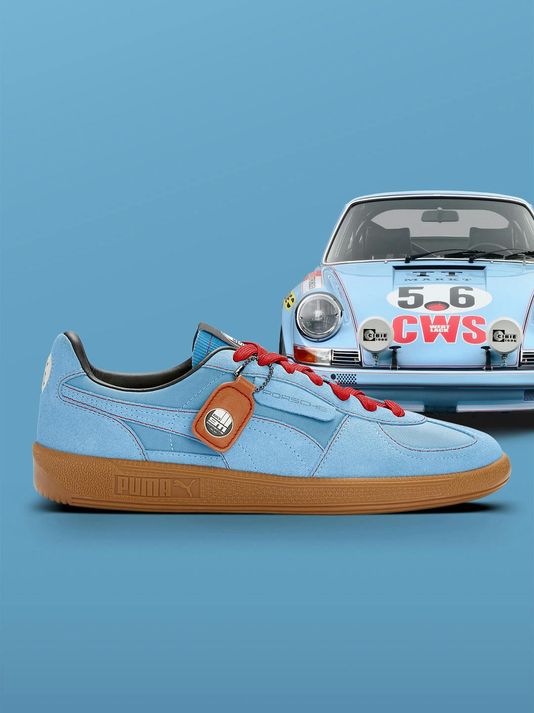 Pictured is a blue Puma sneaker on the side in cooperation with Porsche and in the background is a blue oldtimer with colourful embellishments from Porsche on the front. 