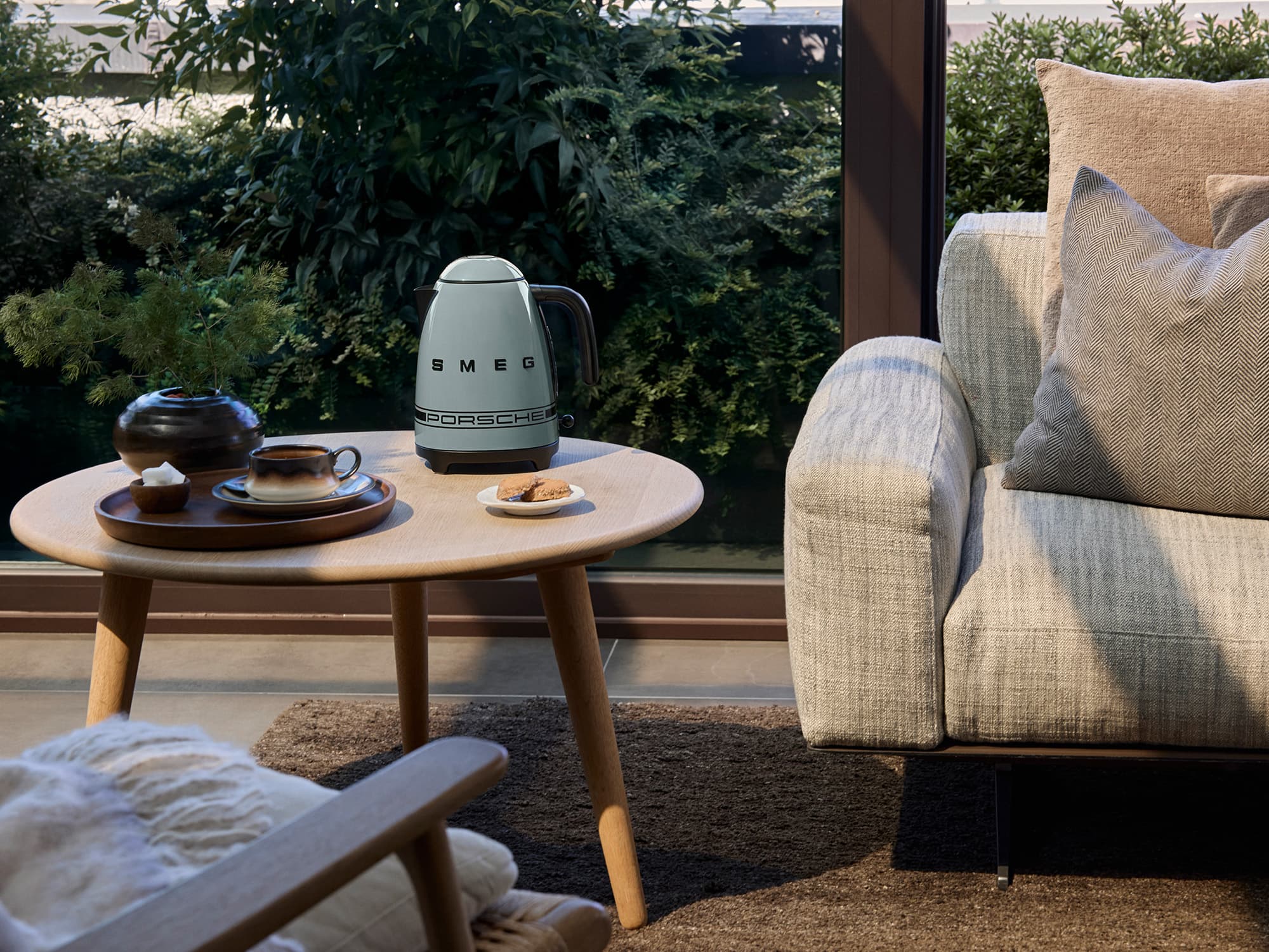 Porsche x Smeg coffee machine in a living room setting with a view of a winter landscape