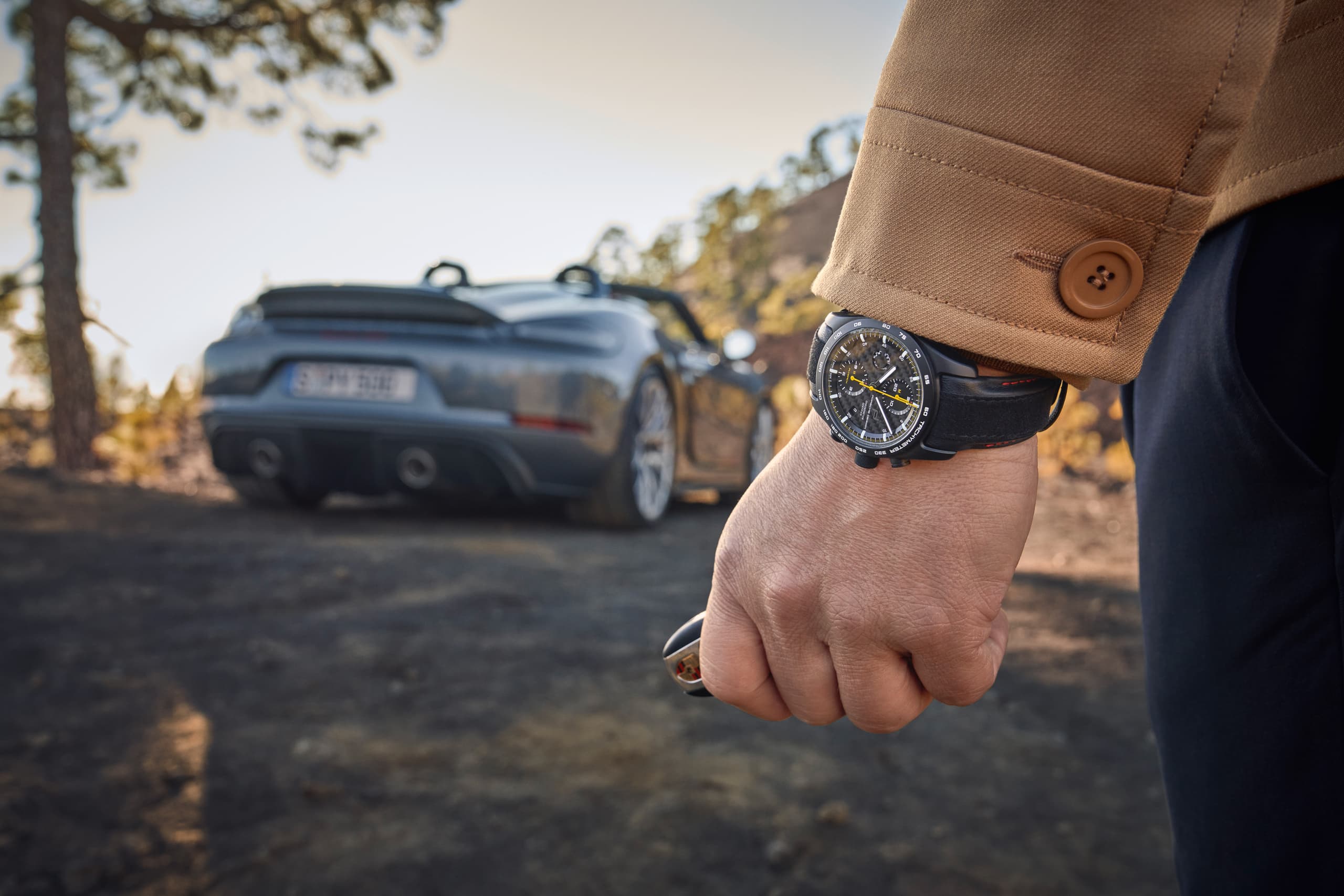 Mężczyzna widziany od tyłu, noszący chronograf Porsche 718 Spyder RS; w tle niebieskie Porsche 718 Spyder.
