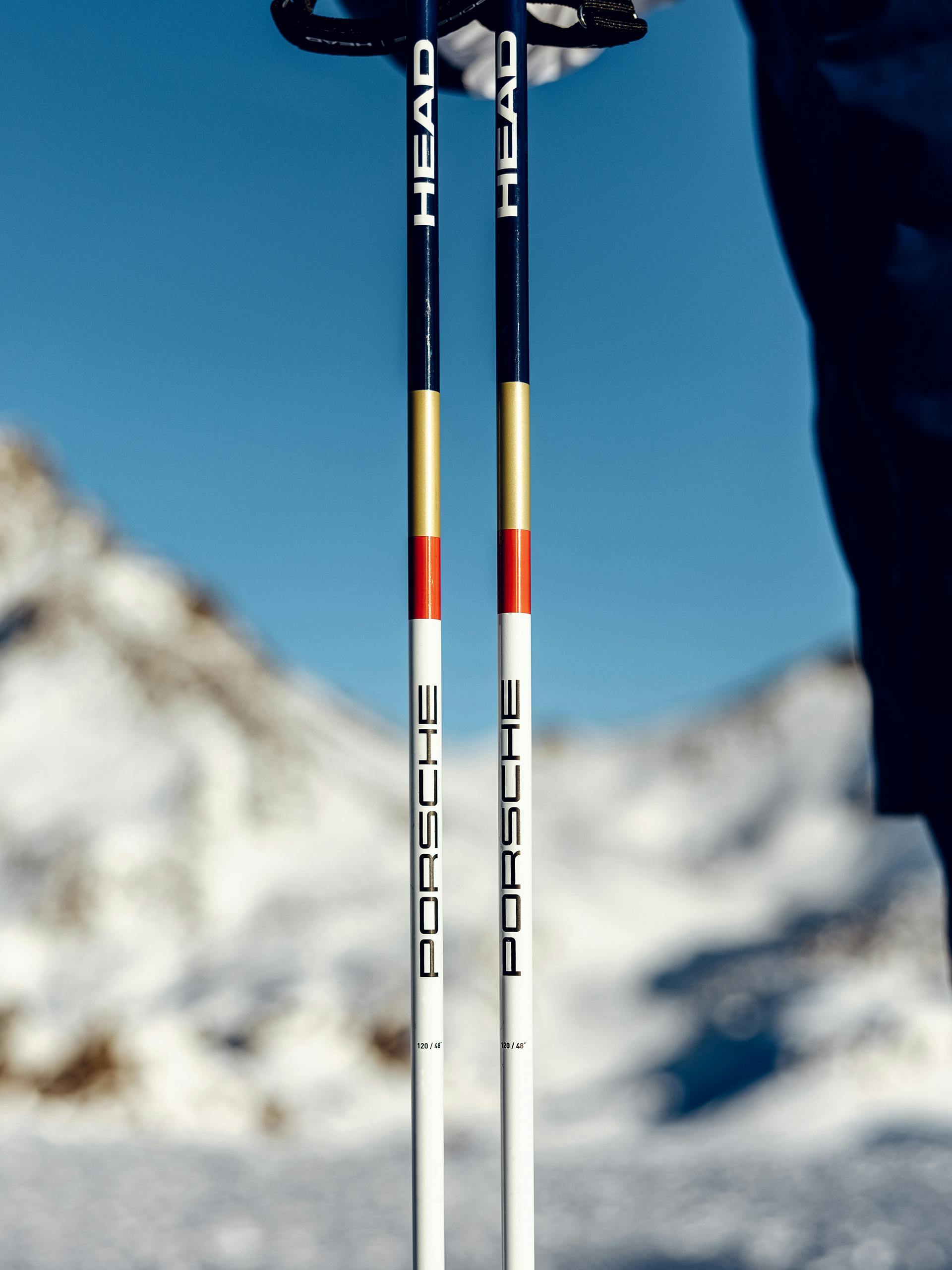 Close up image of the new Porsche HEAD Dakar Carbon Ski Poles with blue sky and mountains in the background.
