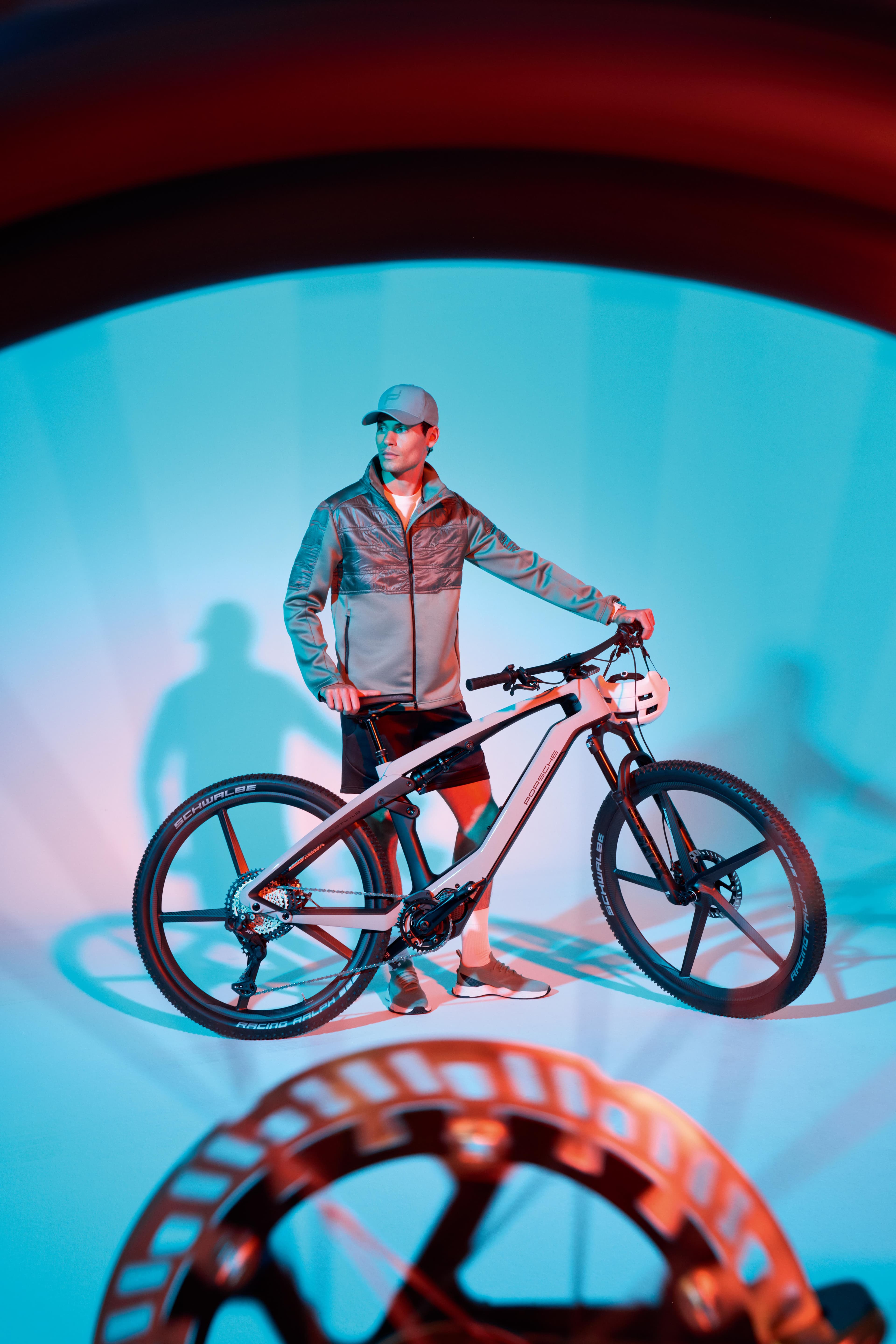 Man in Porsche Design Sportsewear and Porsche eBike Sport photographed through a wheel spoke