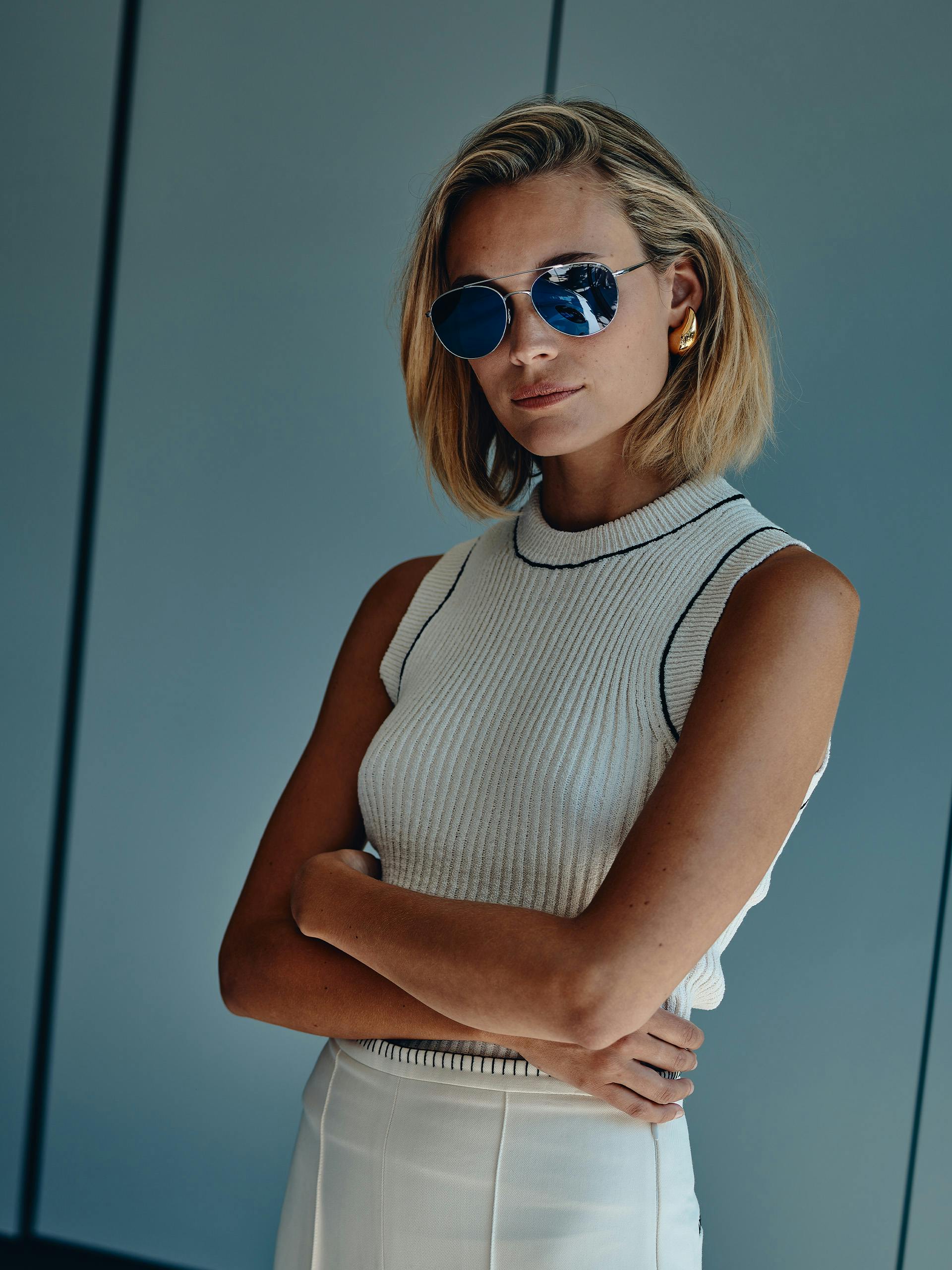 Pictured frontally is a blonde young woman wearing sunglasses