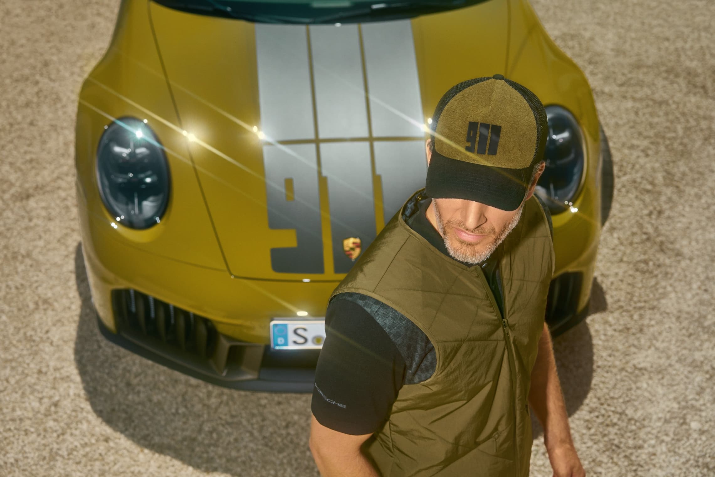 Wearing clothes from the Porsche 911 Spirit 70 collection and walking past a Porsche