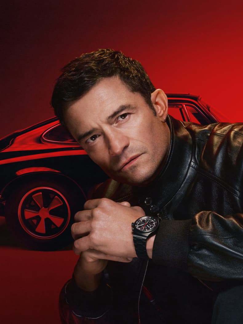 Orlando Bloom luce un reloj Porsche Design Timepieces delante de un Porsche Oldtimer