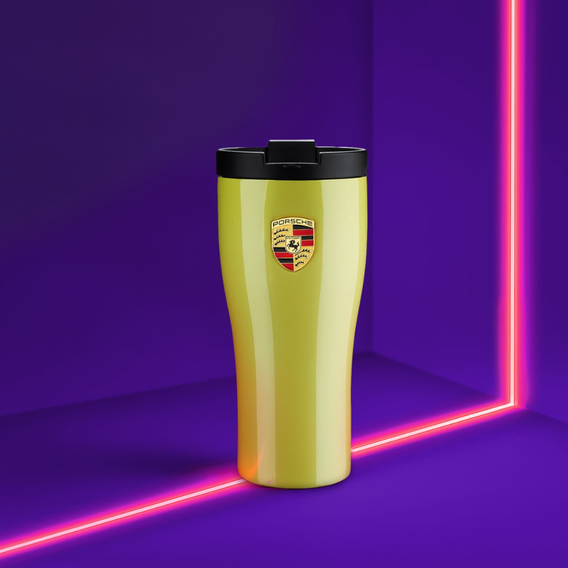 Yellow Porsche travel mug with black lid, logo on front, set against a vibrant purple background with pink neon lines