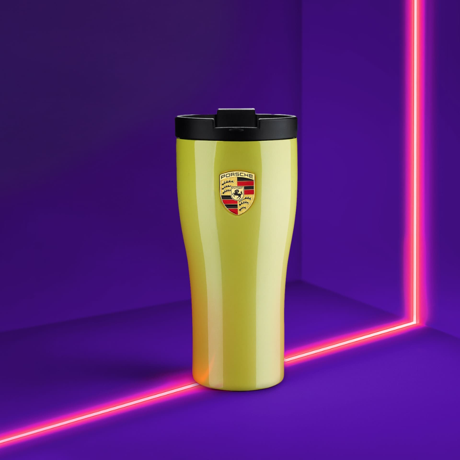 Gelber Porsche-Reisebecher mit schwarzem Deckel, Logo vorne, vor einem lebhaften lila Hintergrund mit pinken Neonlinien.