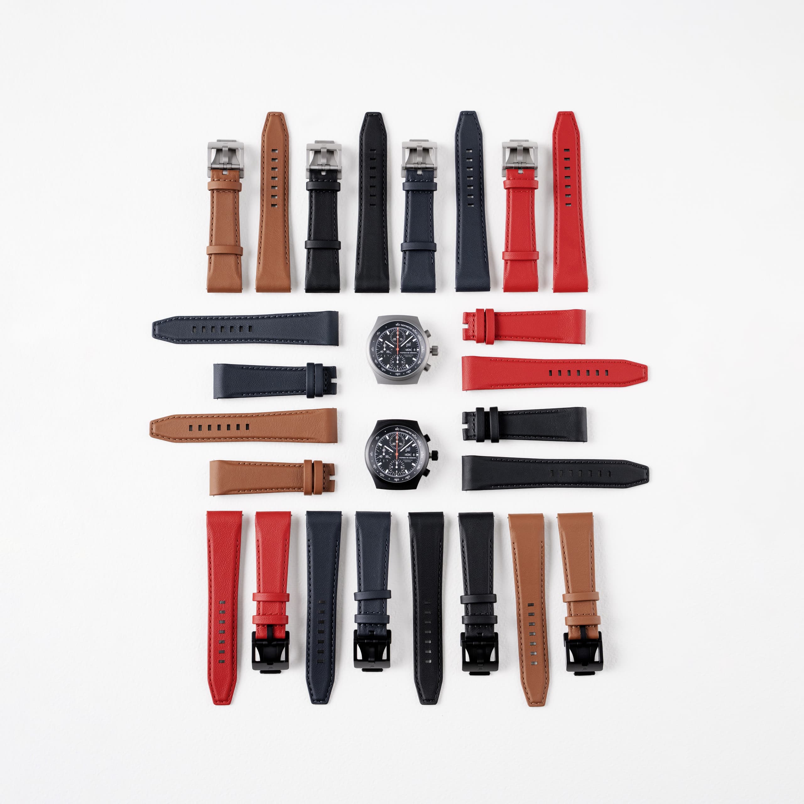 Various leather watch straps with two chronograph watches on a white background.