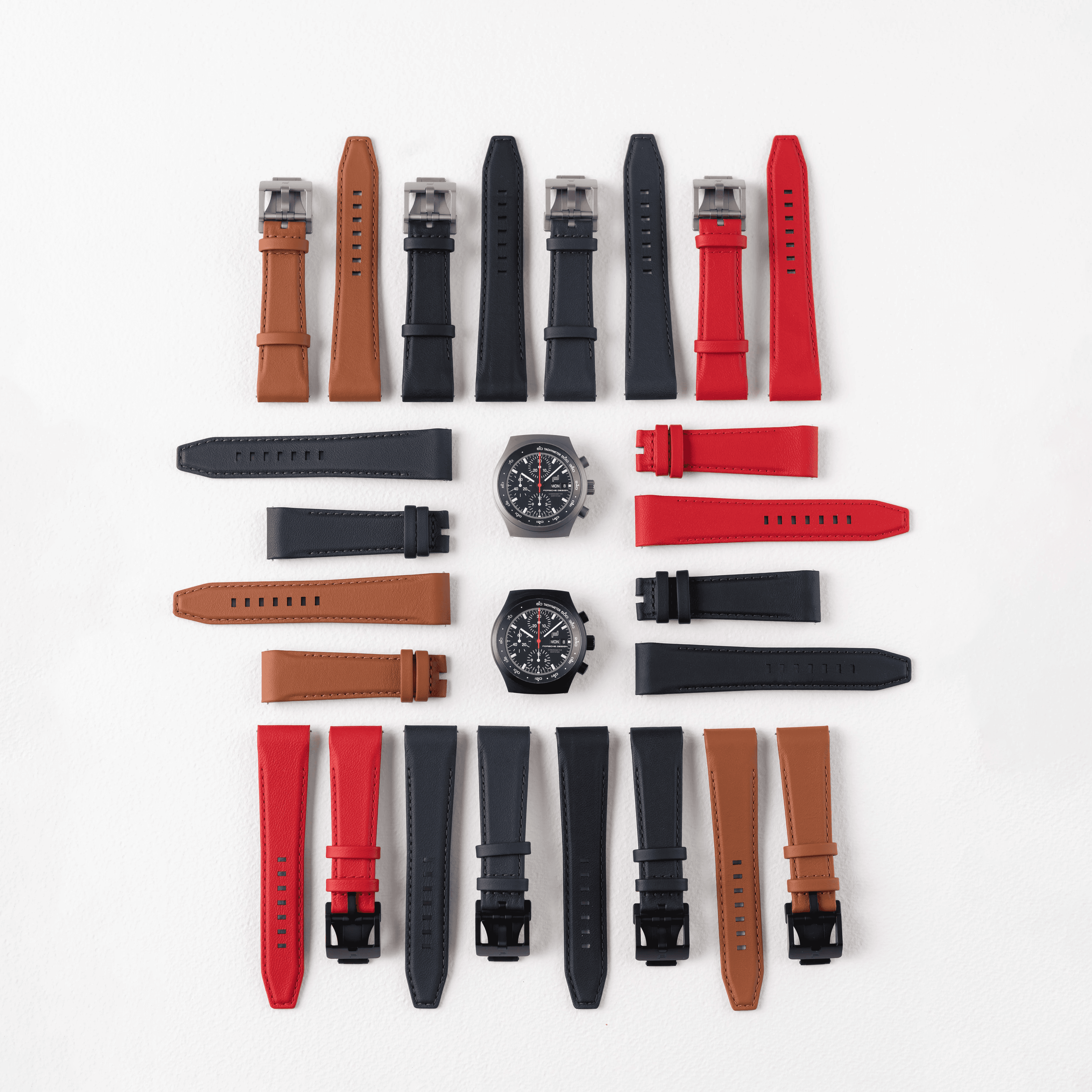 Varios correas de reloj de cuero con dos relojes cronógrafo sobre fondo blanco.