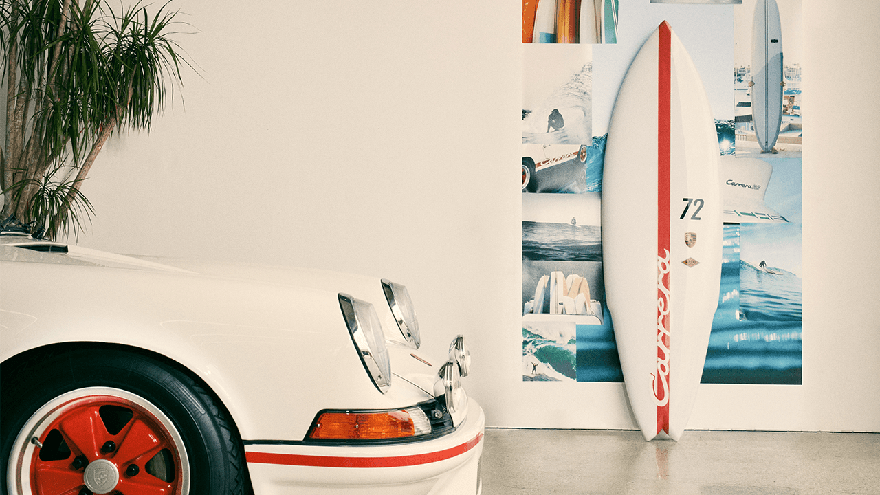 Porsche 911 in front and Porsche White and red Surfboard in the back