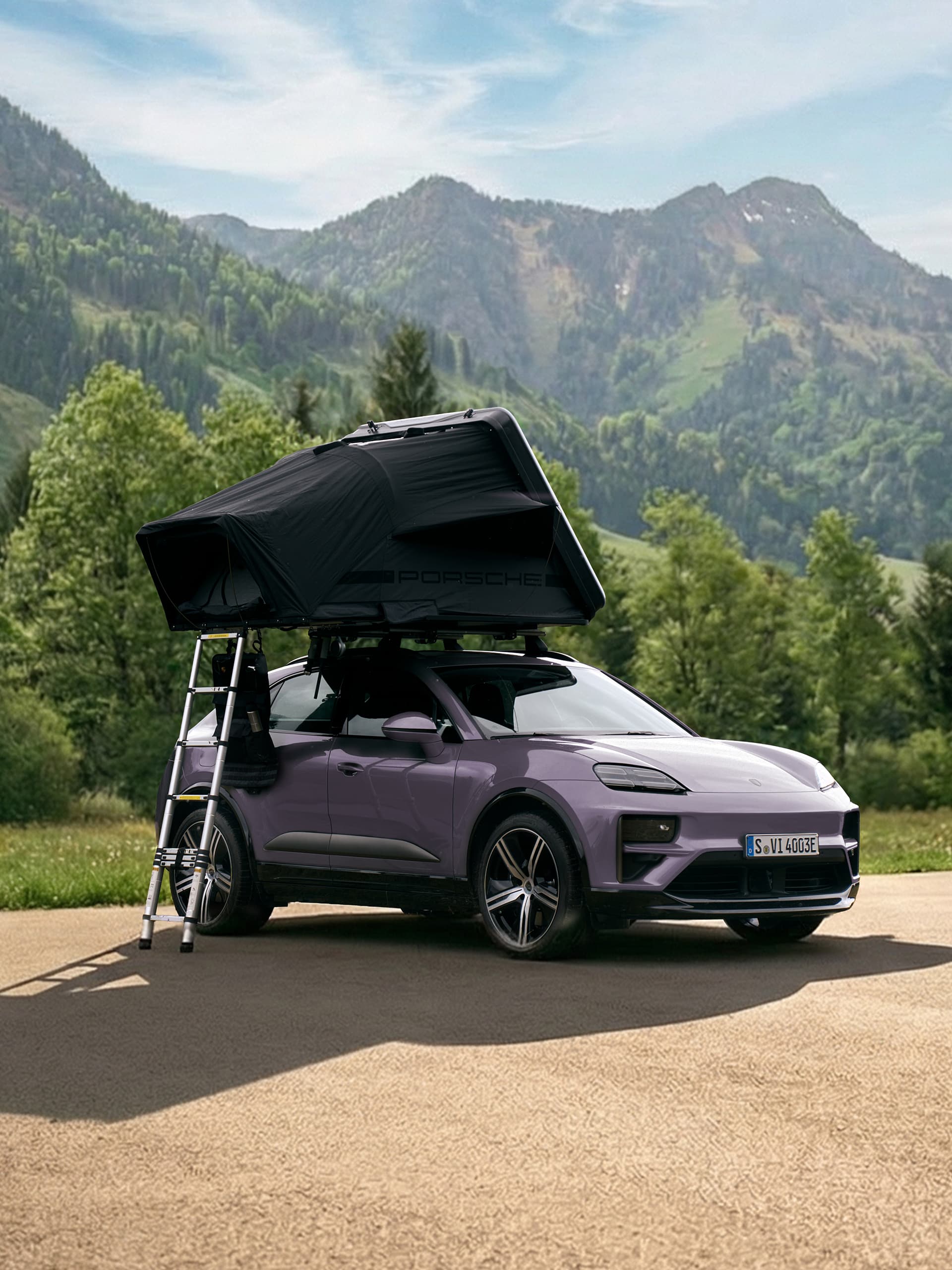 Fioletowe Porsche z namiotem dachowym i drabiną, na tle malowniczych gór pod błękitnym niebem.