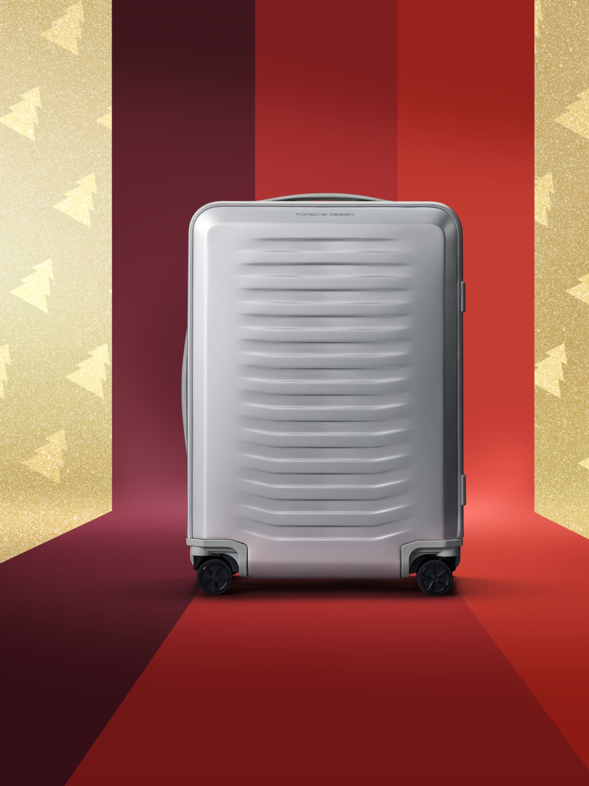 Silver suitcase with wheels on a red and gold festive background with tree patterns