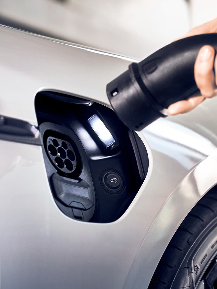 Close up of a Porsche with a person holding a charging cable
