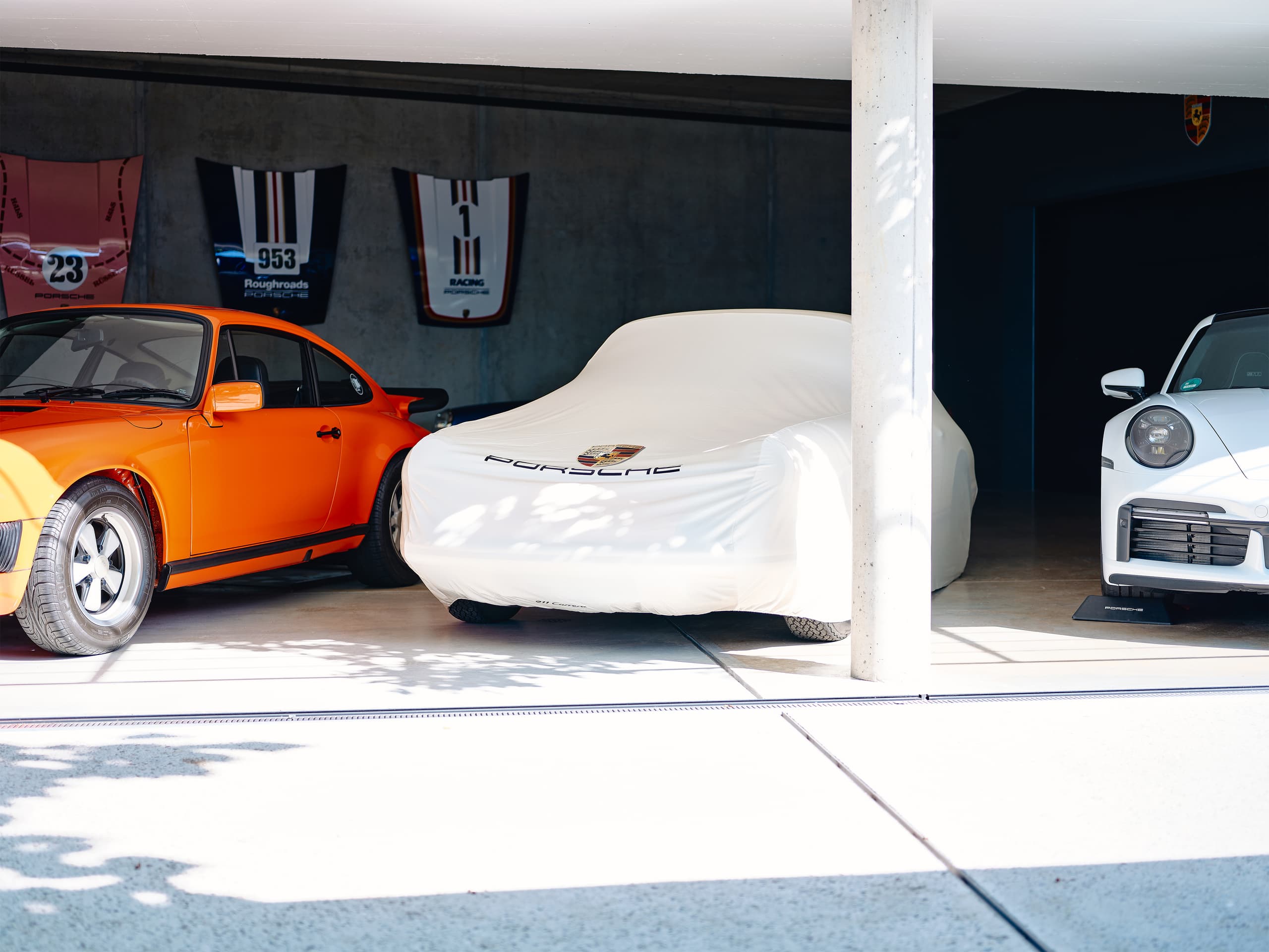 You can see a car beneath a beige car cover with a porsche crest on it