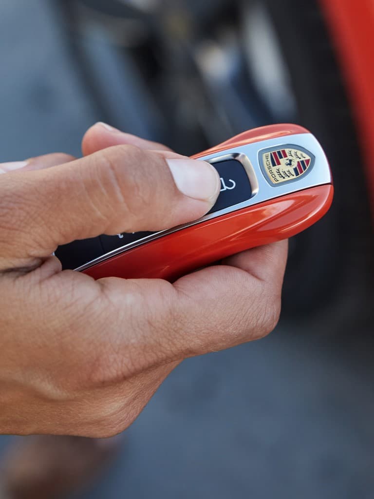Man holding red Porsche Key in his hand
