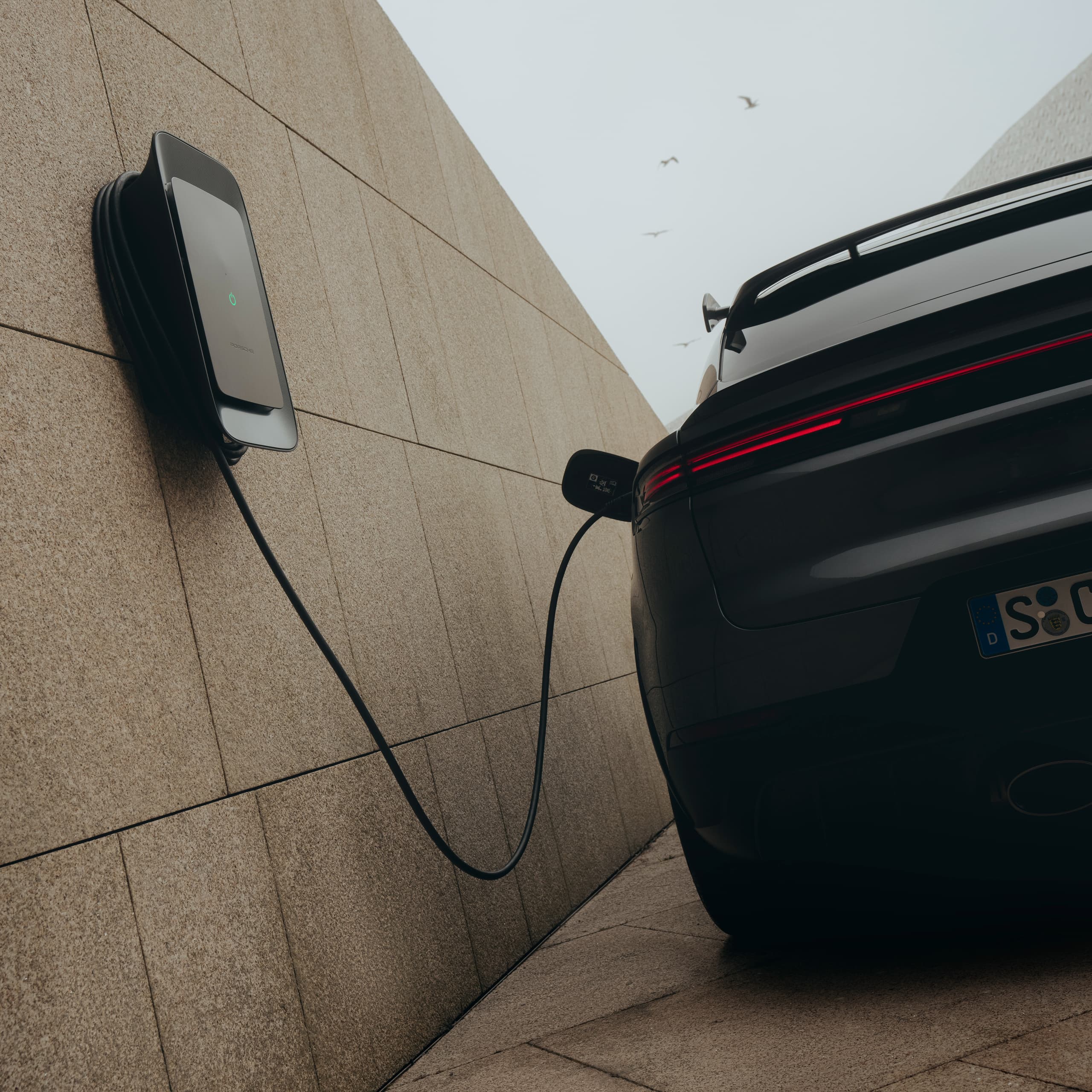 You can see a Porsche Wallbox on a wall next to a car