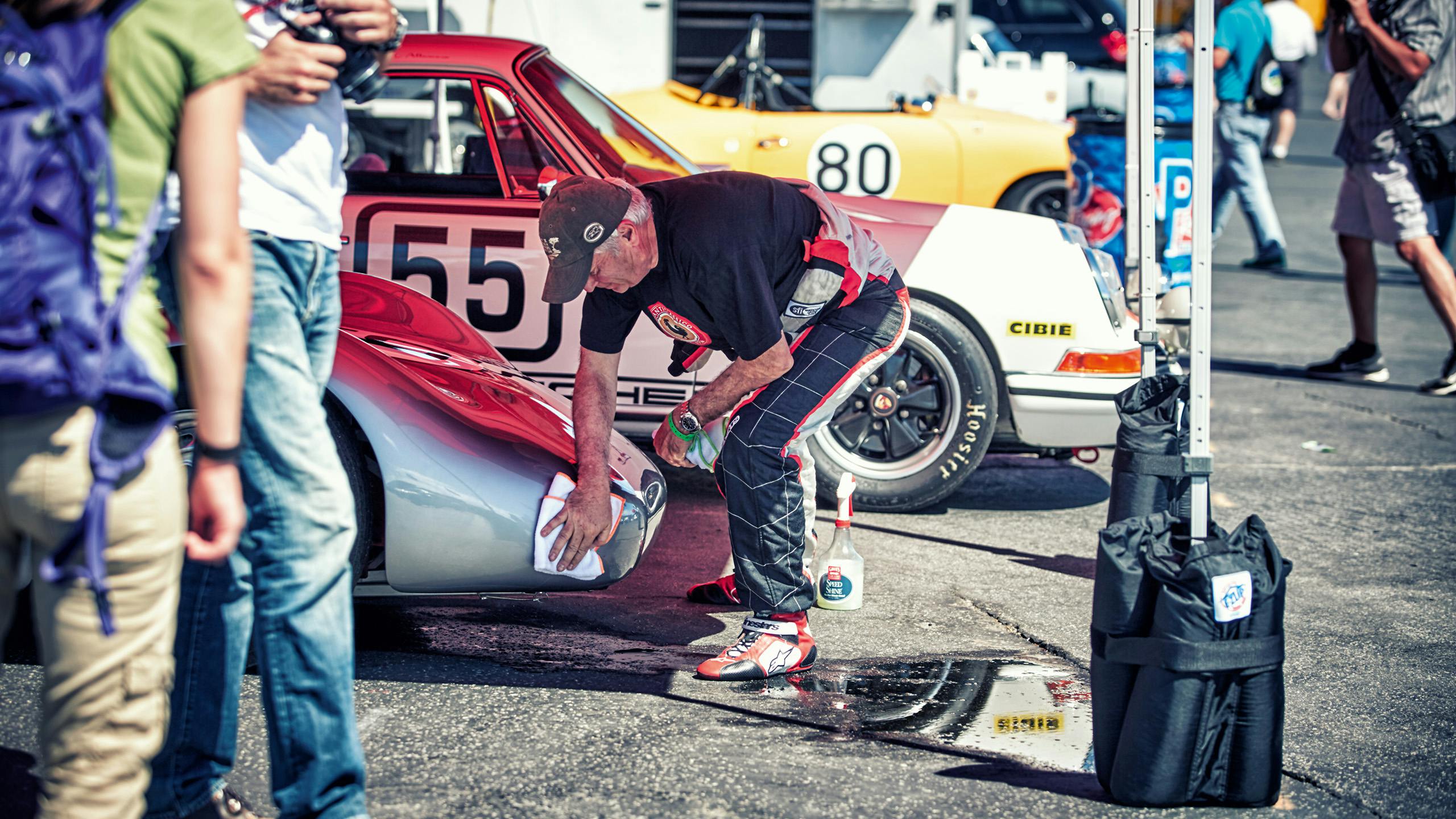 To see is a man as he cleans a vintage Porsche on a racetrack