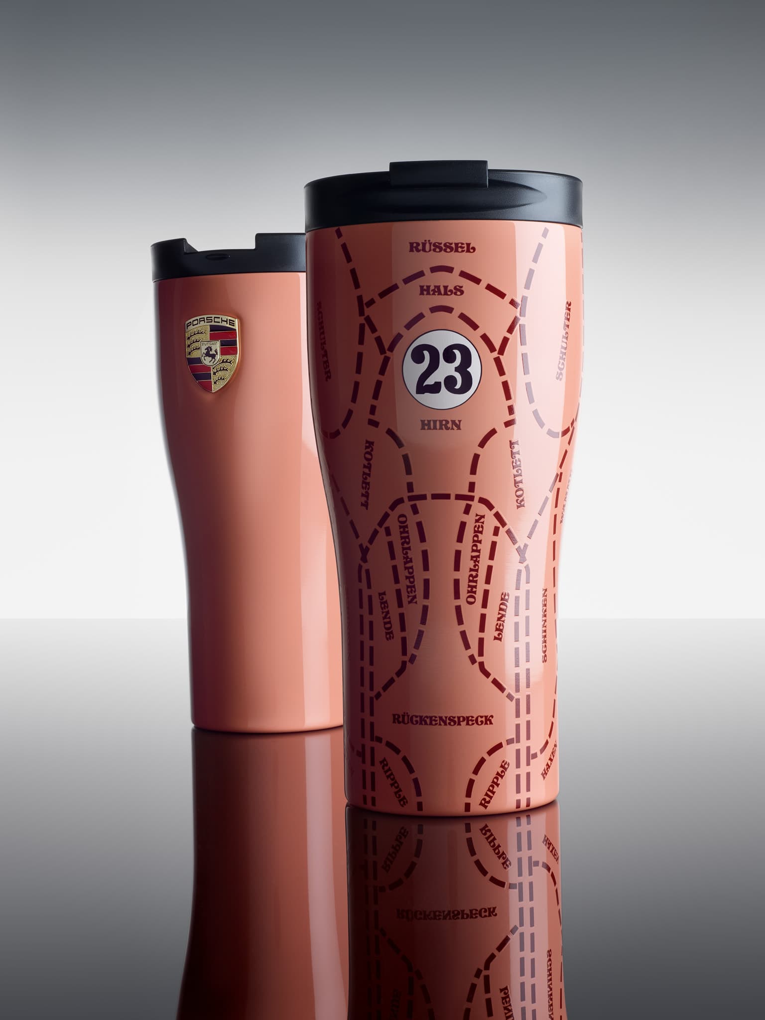 Two pink travel mugs with black lids; one features a Porsche logo, the other has a racing design with the number 23.