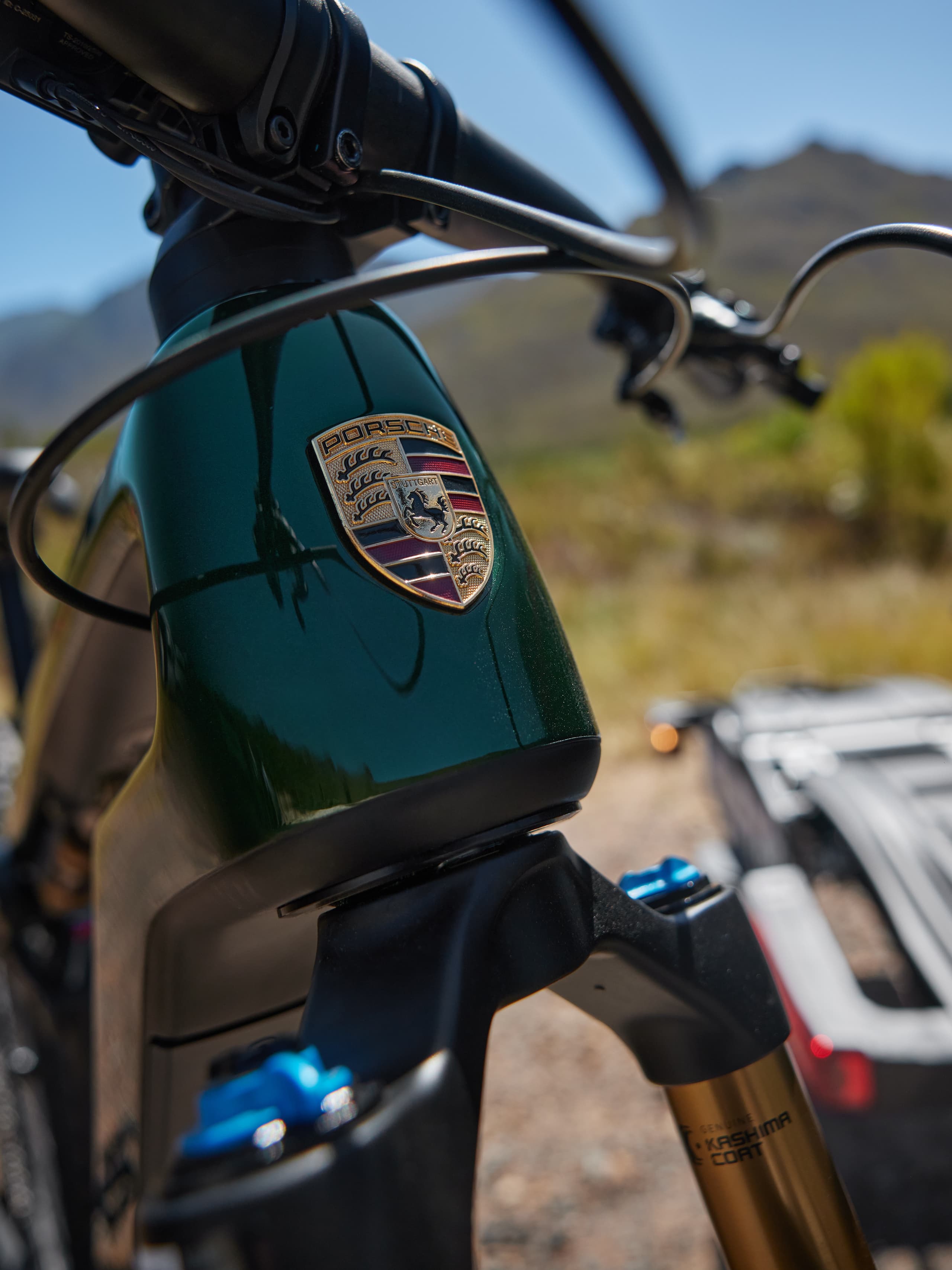 Gros plan du cadre de vélo Porsche vert avec logo, sur un paysage extérieur flou.