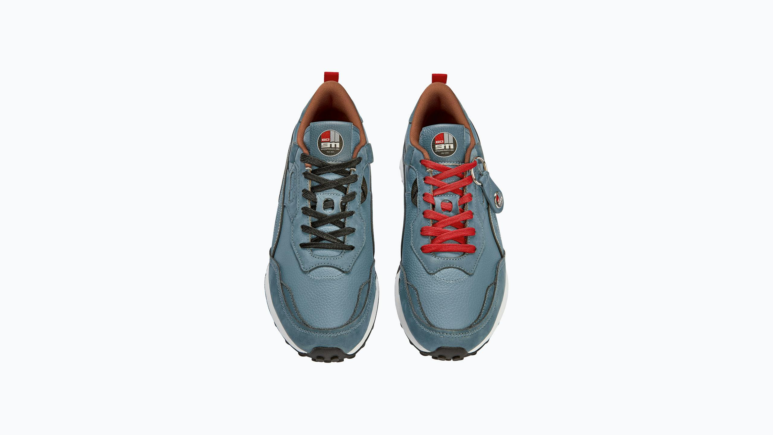 Pictured frontally is the blue Heritage sneaker from Porsche in cooperation with Puma. The right shoe has red laces and the left sneaker has black laces.