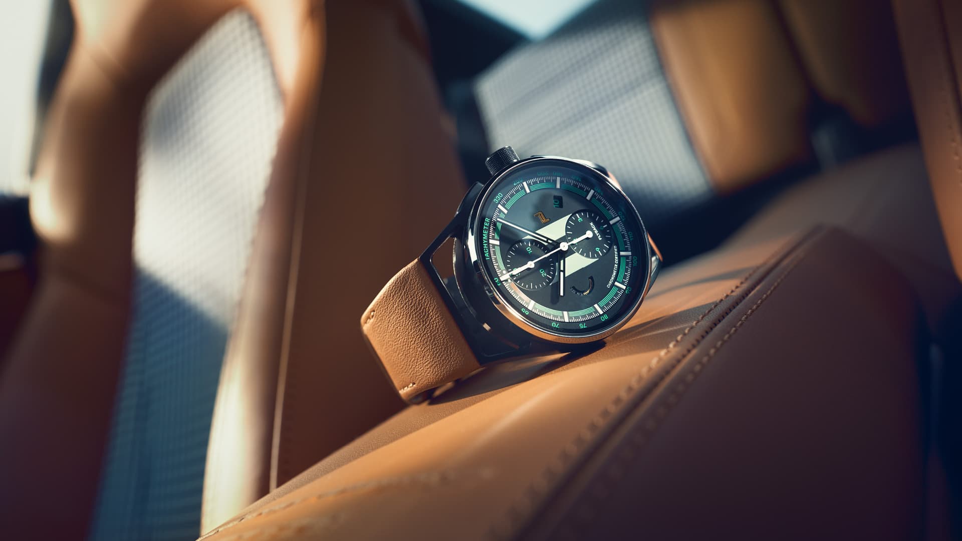Chronograph 911 Sport Classic mit braunem Lederarmband auf einem braunen Ledersitz