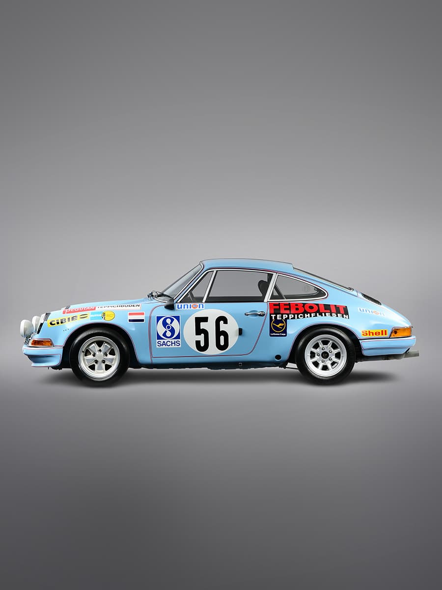 You can see a blue-coloured vintage car from the side with colourful decorations.
