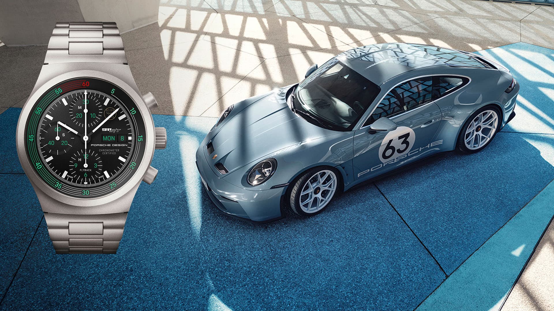 A silver Porsche Design chronograph watch next to a blue Porsche 911 with the number 63 on a blue background