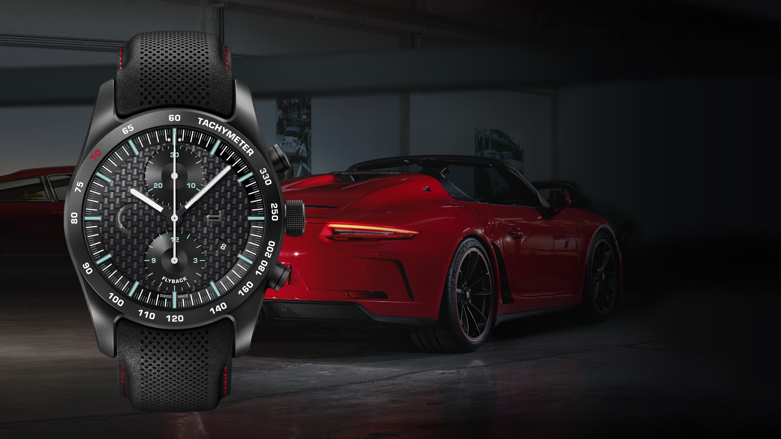 Na zdjęciu zegarek na rękę Porsche Chronograph 911 Speedster z czarnym paskiem, na tle czerwonego Porsche 911.