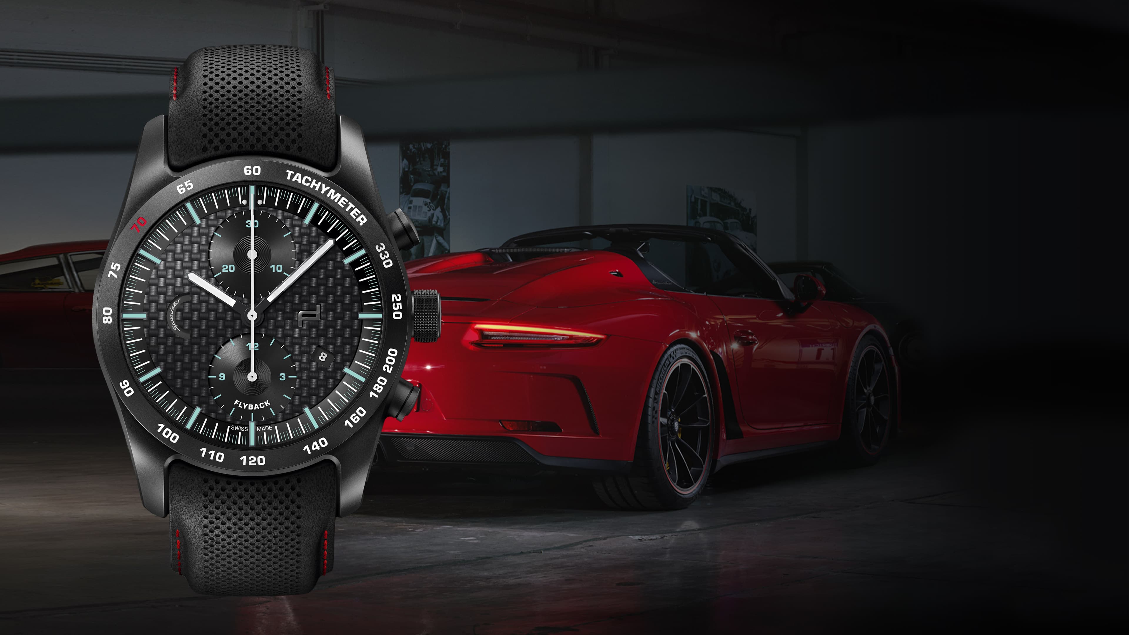 Pictured is the Chronograph 911 Speedster Porsche wristwatch with a black strap and a red Porsche 911 in the background