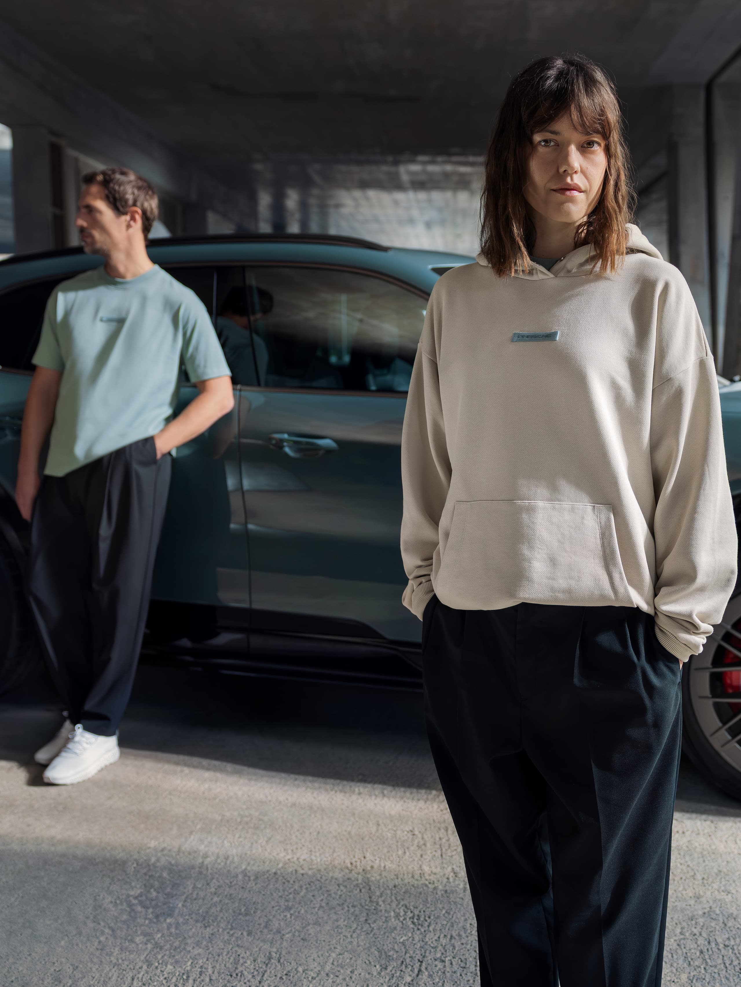 Eine Frau und ein Mann stehen vor einem petrolfarbenen Porsche Macan.