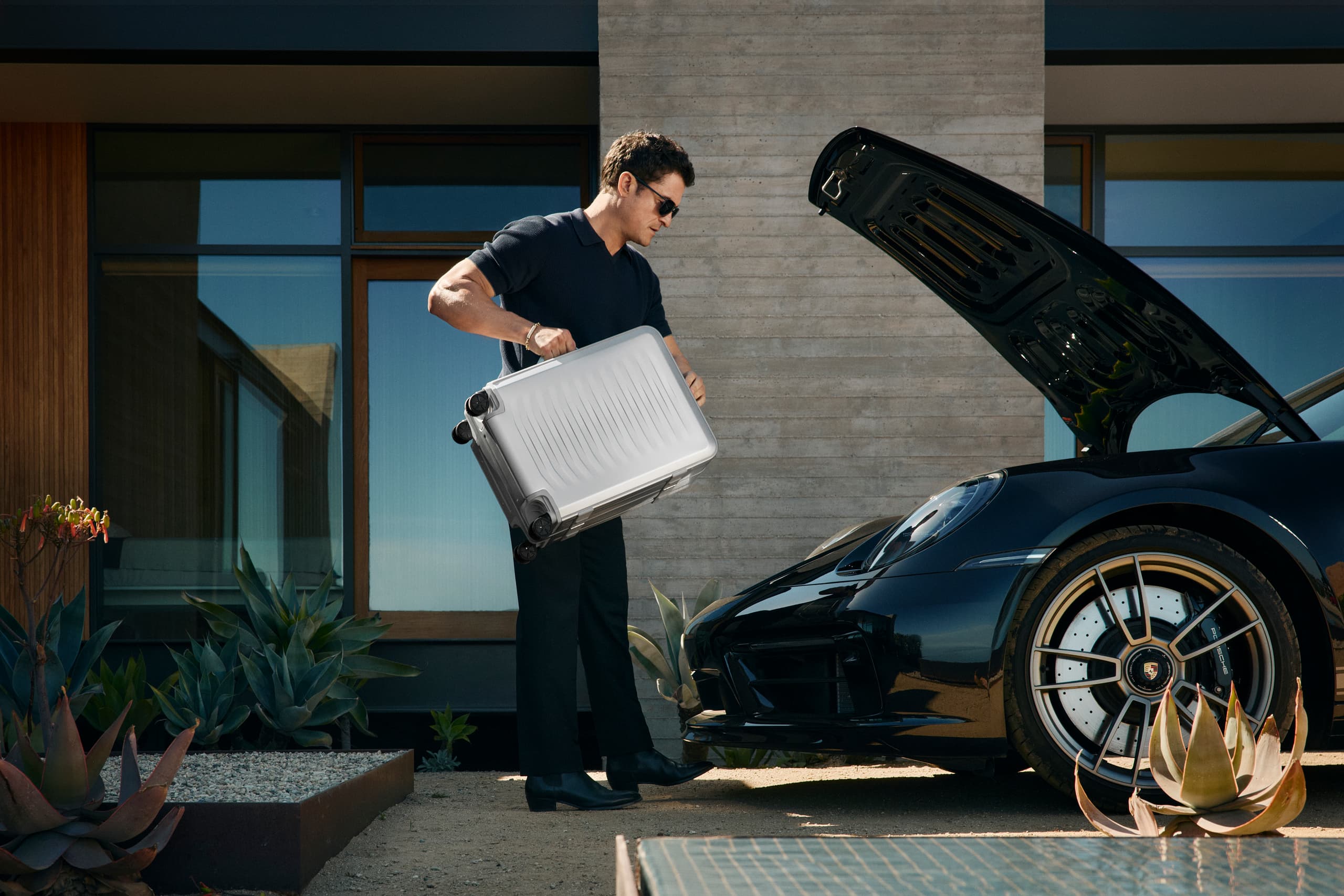 Orlando Bloom with the Roadster Aluminum Trolley putting it in a Porsche 911 Targa trunk