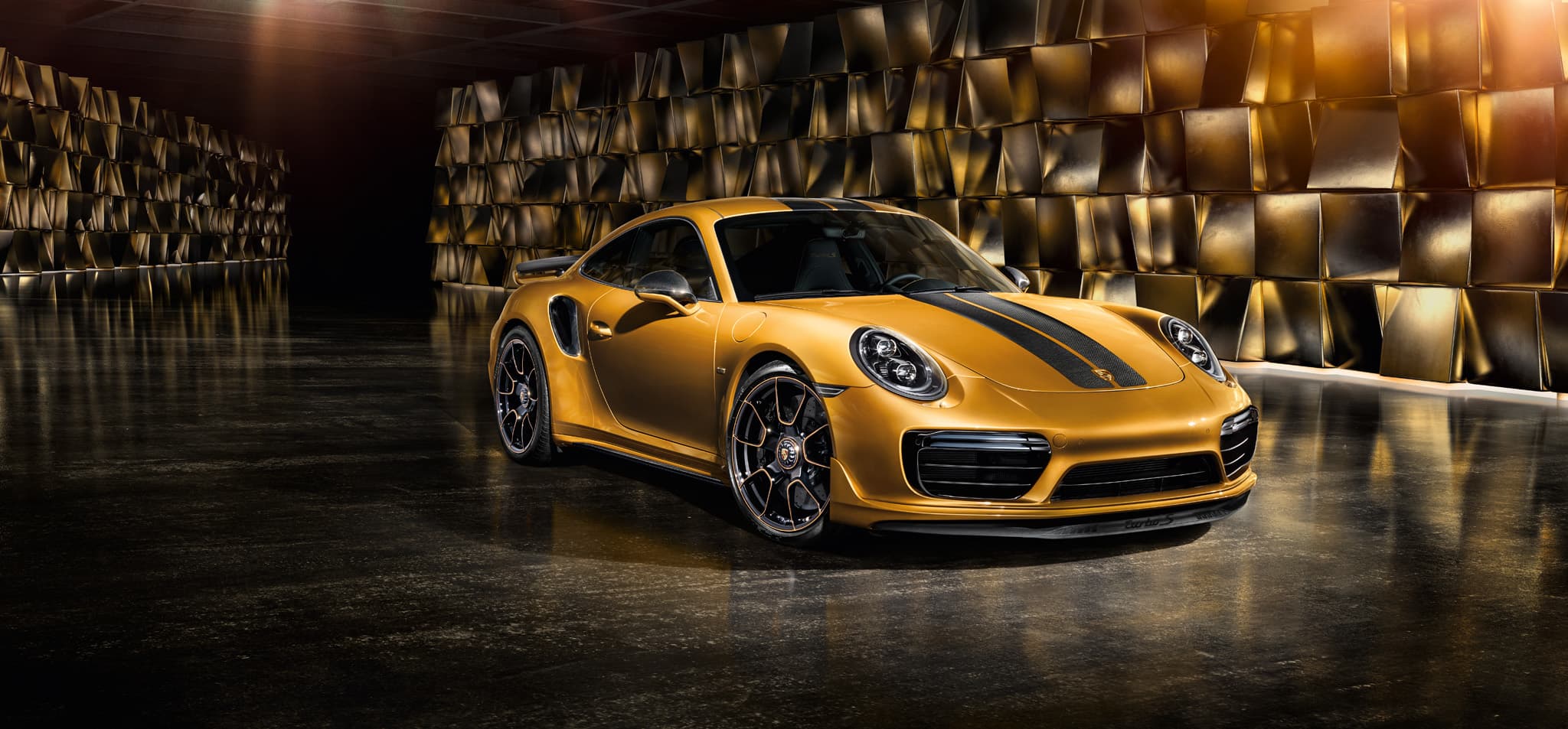 Złoty Porsche 911 Turbo S z czarnymi pasami.