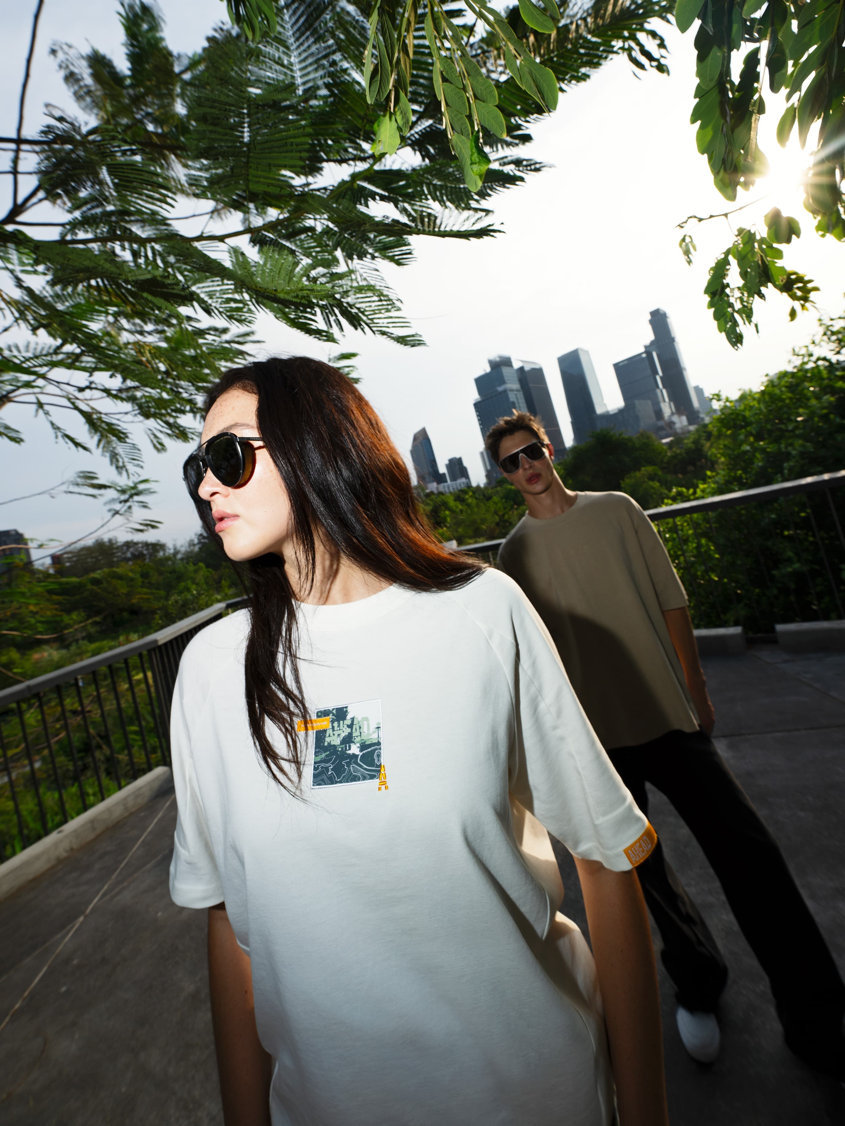 A woman and a man look into the distance, while wearing the Porsche Summer 2026 Collection, including shirts and sunglasses.
