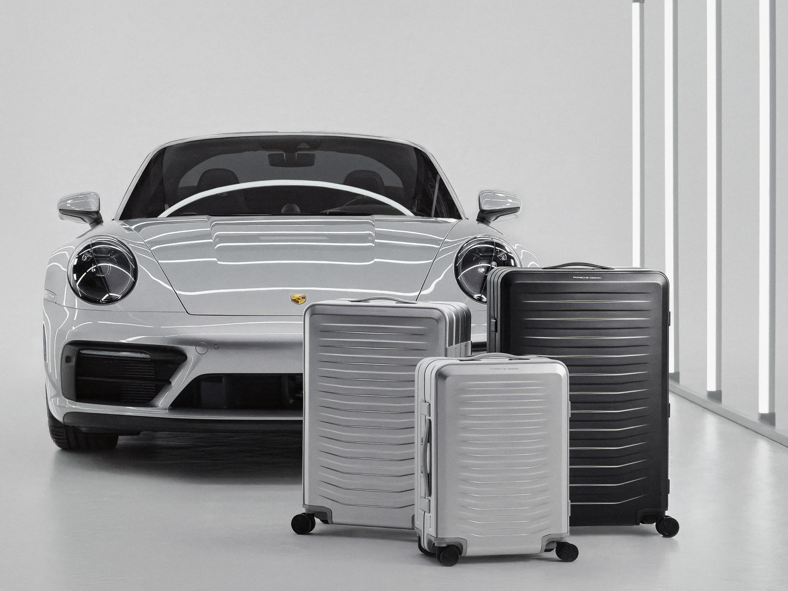 Linia produktów Porsche Design Roadster Aluminum na tle samochodu Porsche