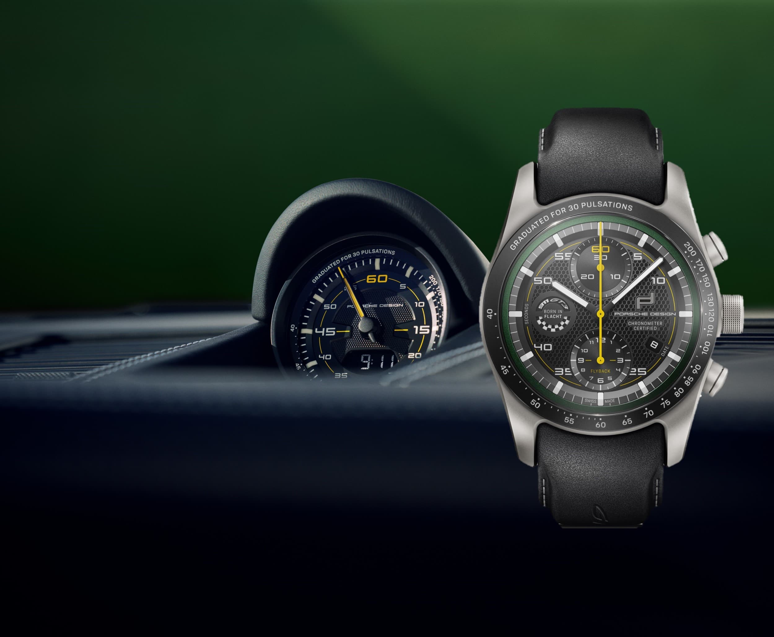 Zegarek Porsche Design Chronograph z czarnym skórzanym paskiem i żółtymi akcentami, pokazany obok wskaźnika samochodowego na zielonym tle.