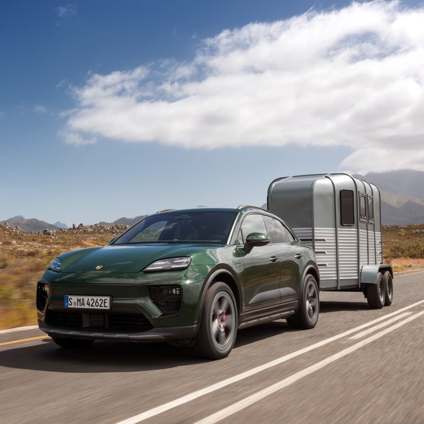View of the rear of a darkgreen Porsche Macan in a dusty landscape