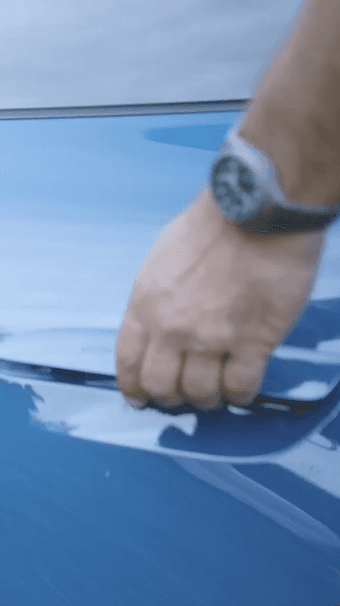 A person is opening the door of a blue Porsche car