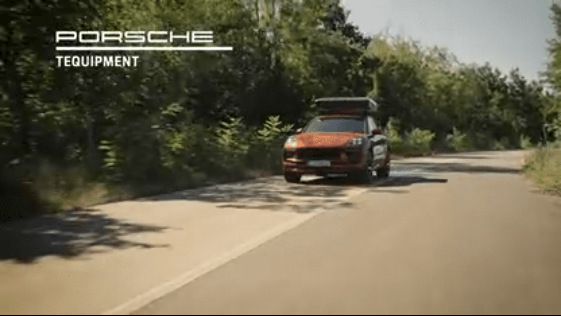 Orange Porsche car is driving on a road, Porsche Tequipment brand logo at the top